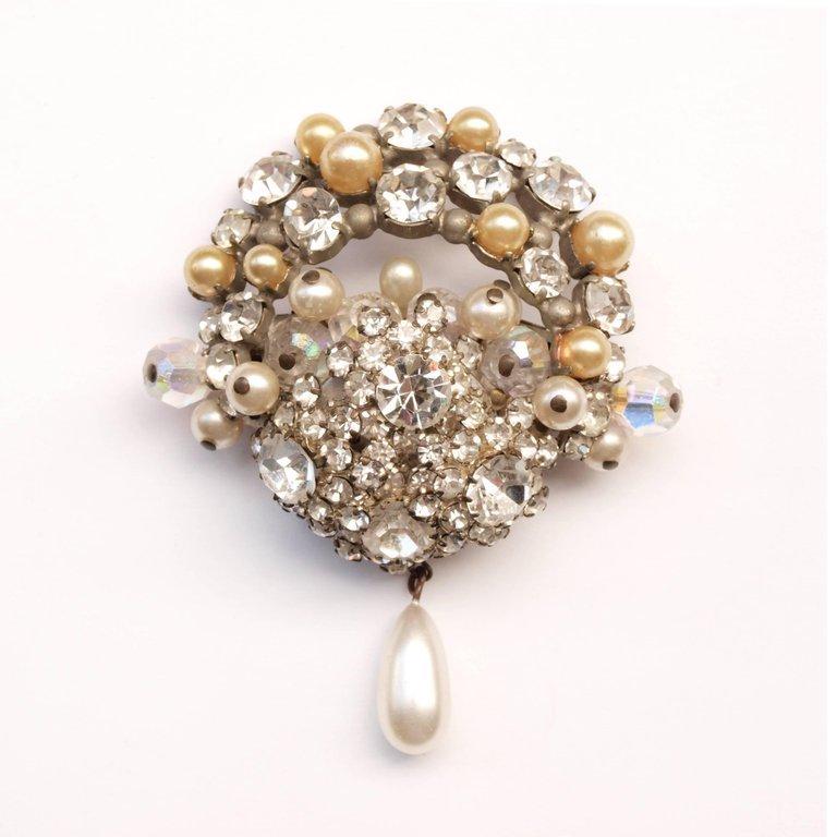 Unworn 1950's brooch with original label that reads; Marcel Gerard Paris.
An eye-catching piece of mid 20th century costume Jewelry featuring clustered large and small rhinestones and nacre pearls with one pendant teardrop faux pearl. Supposedly