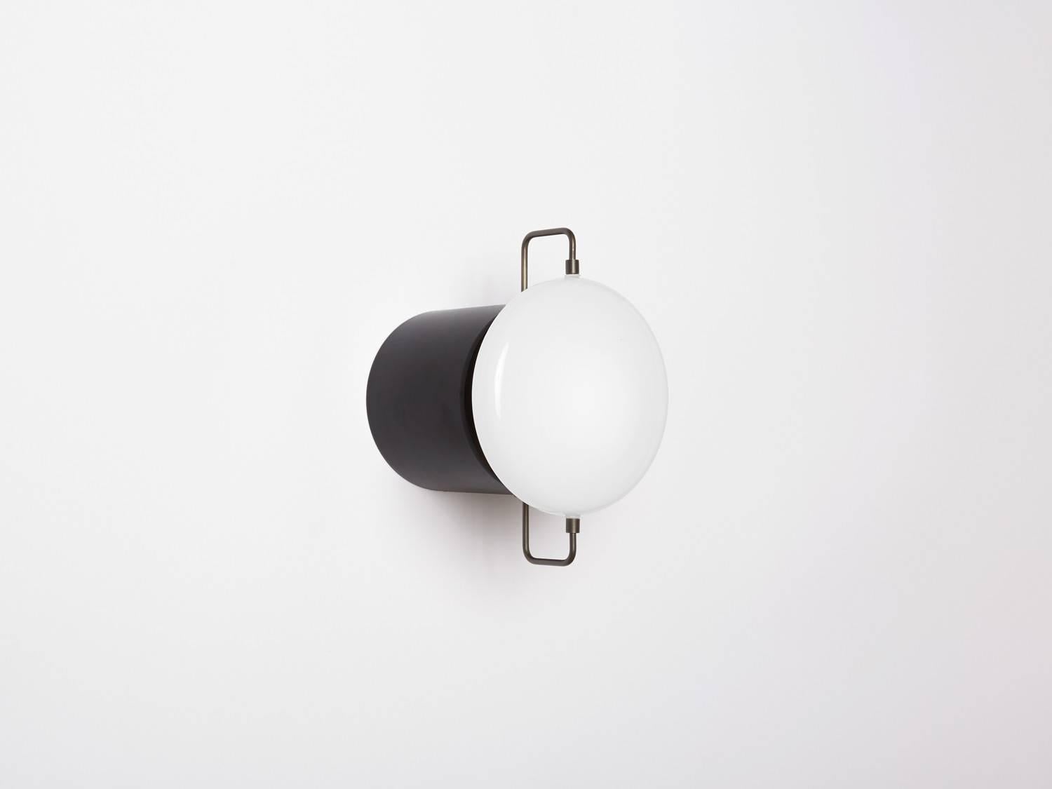 Park I can be utilized as a wall sconce or flush-mount fixture. Referencing porcelain fixtures produced during the pre-war period, the fixture incorporates delicate metal rods that suspend a handblown milk glass form. Made in the USA, UL listed.