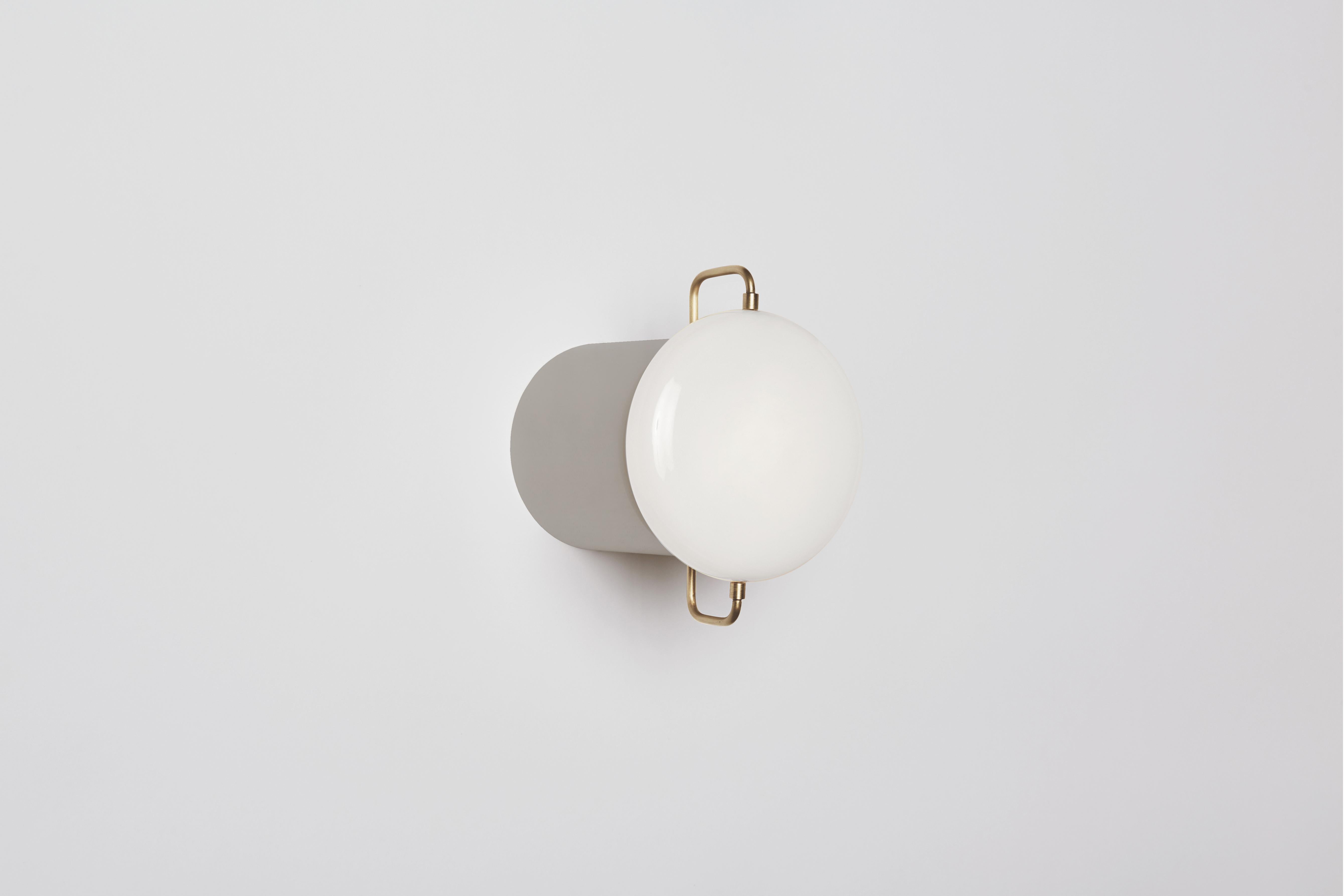 Park I can be utilized as a wall sconce or flush-mount fixture. Referencing porcelain fixtures produced during the pre-war period, the fixture incorporates delicate metal rods that suspend a hand blown milk glass form. Made in the USA, UL listed.