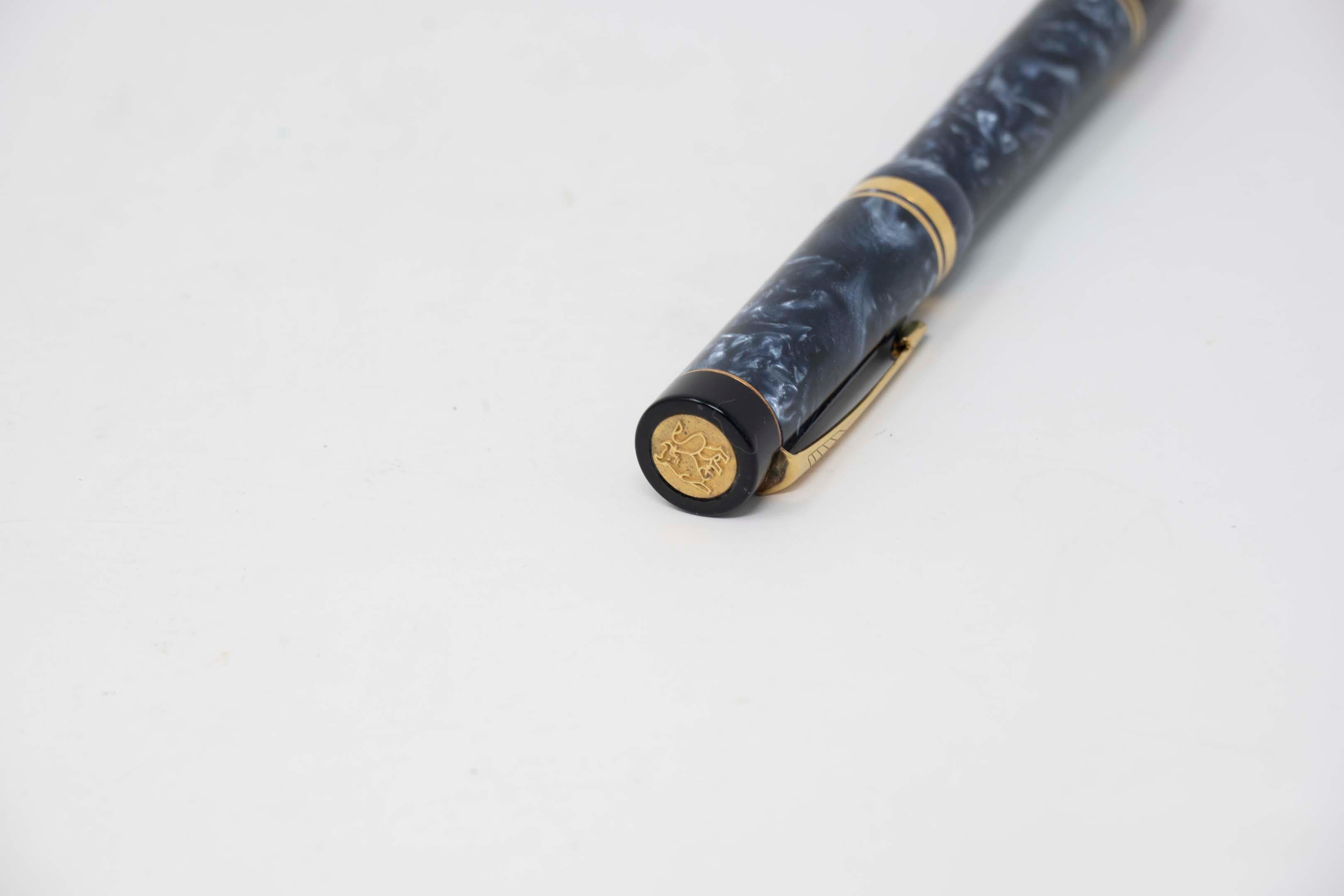 Stylo plume Parker Duofold bleu marbré avec plume or 18k, 13,5 cm de long. Fabricant Parker, fabriqué au Royaume-Uni. Le bouchon présente le motif du taureau doré, en bon état ; la recharge doit être remplacée.
