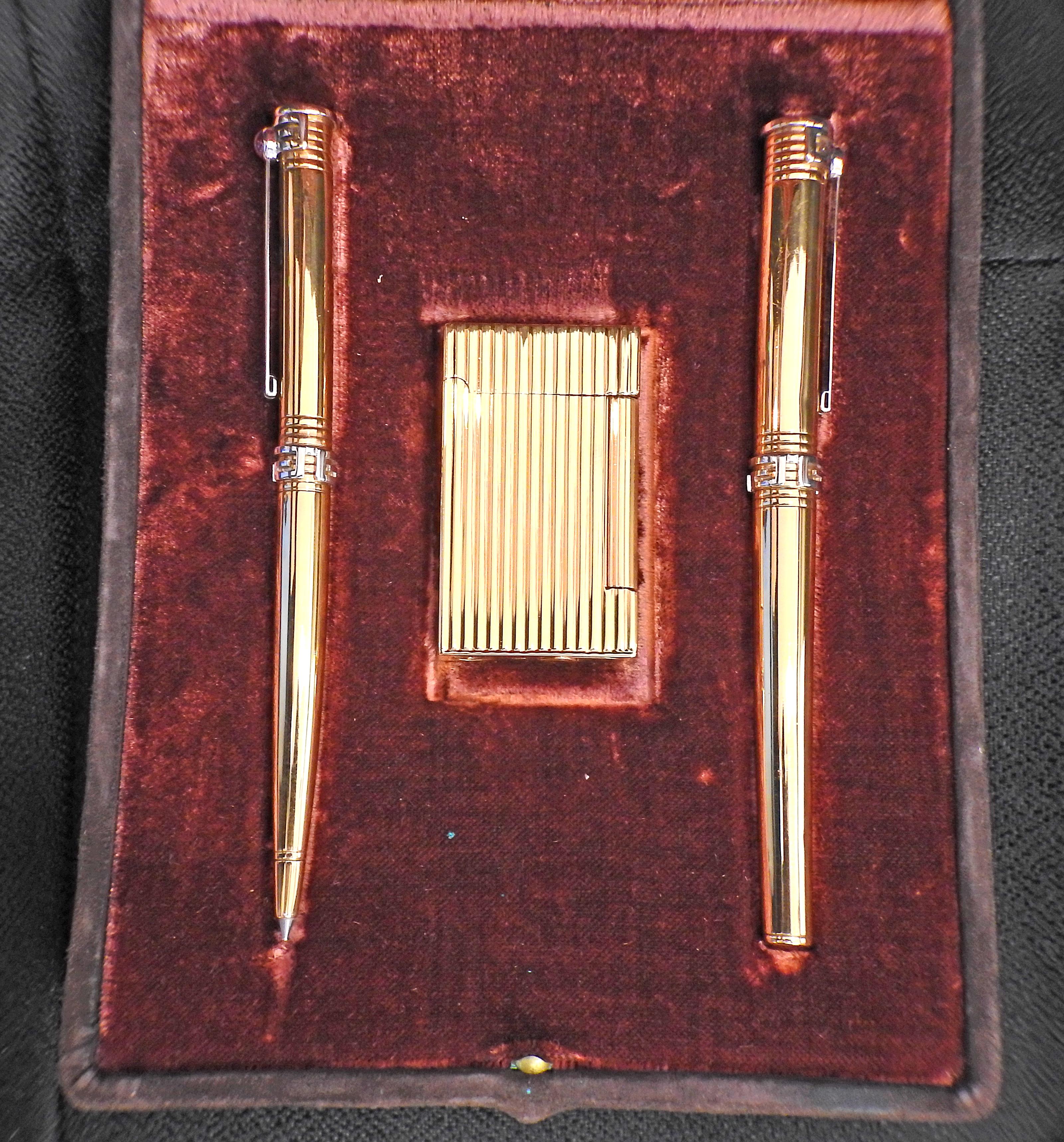 18k Gold zwei Schreibgeräte (ein Rollerball und ein Füllfederhalter) und ein Feuerzeug von Parker, in Originalverpackung. Die Stifte sind jeweils 130 mm lang, das Feuerzeug misst 55 mm x 32 mm x 9 mm. Stifte mit Cabochon-Rubin auf der Kappe