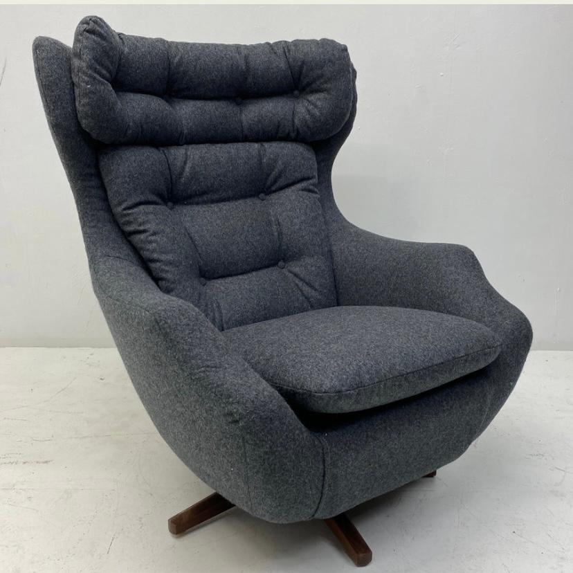 A stunning British midcentury Parker Knoll Statesman lounge chair. The lounge chair has a teak swivel base & is completely professionally reupholstered in dark grey British Abraham Moon wool fabric. The chair has fabric covered buttons to the seat