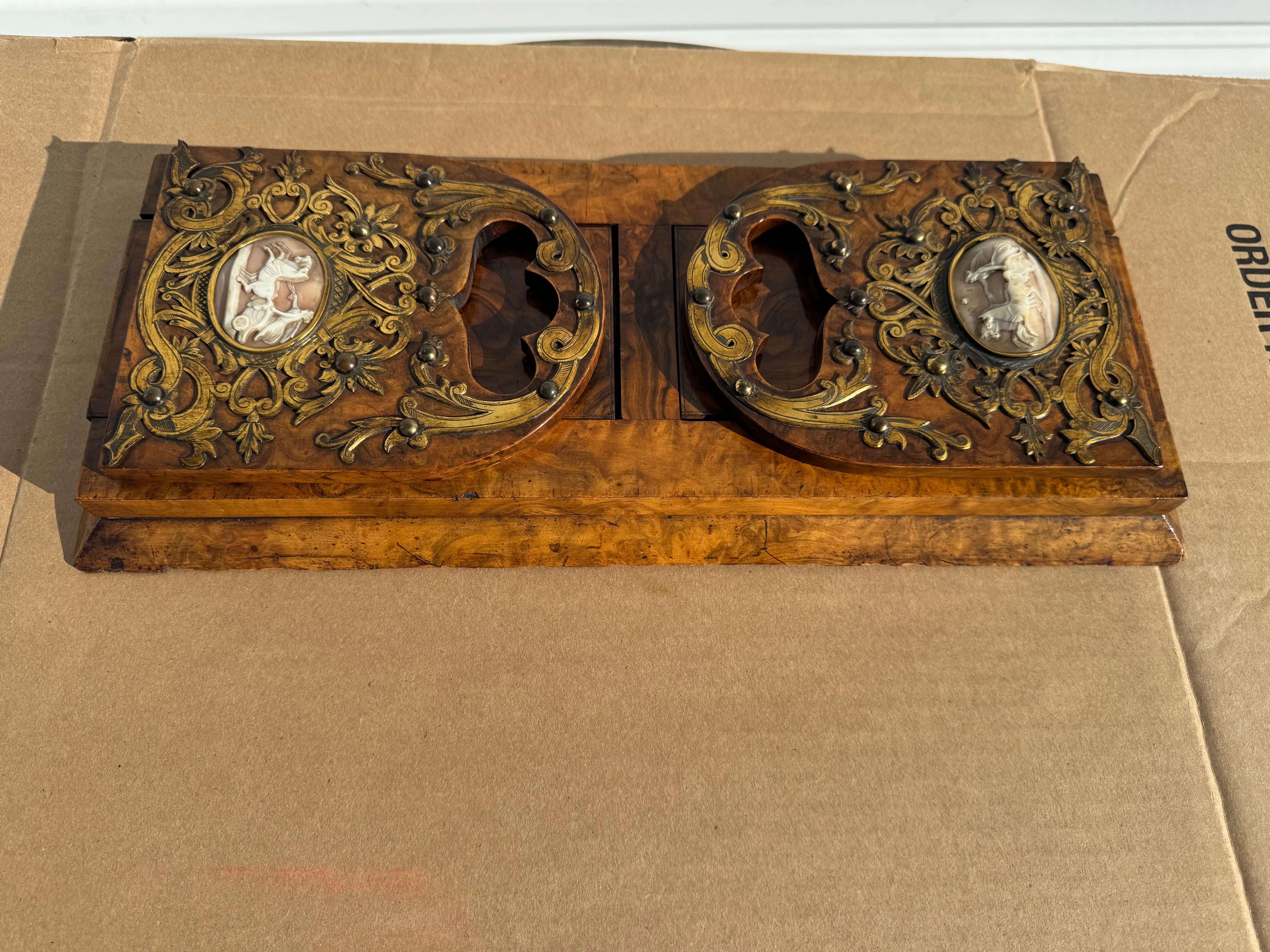This is a beautiful Vicorian period book gliding shelf.
Its made of a nice burlwood and has beautiful brass filigree with
cameos on the bookends. The bookends extend to hold more books.
the piece was crafted in England by Parkins and Gotto.