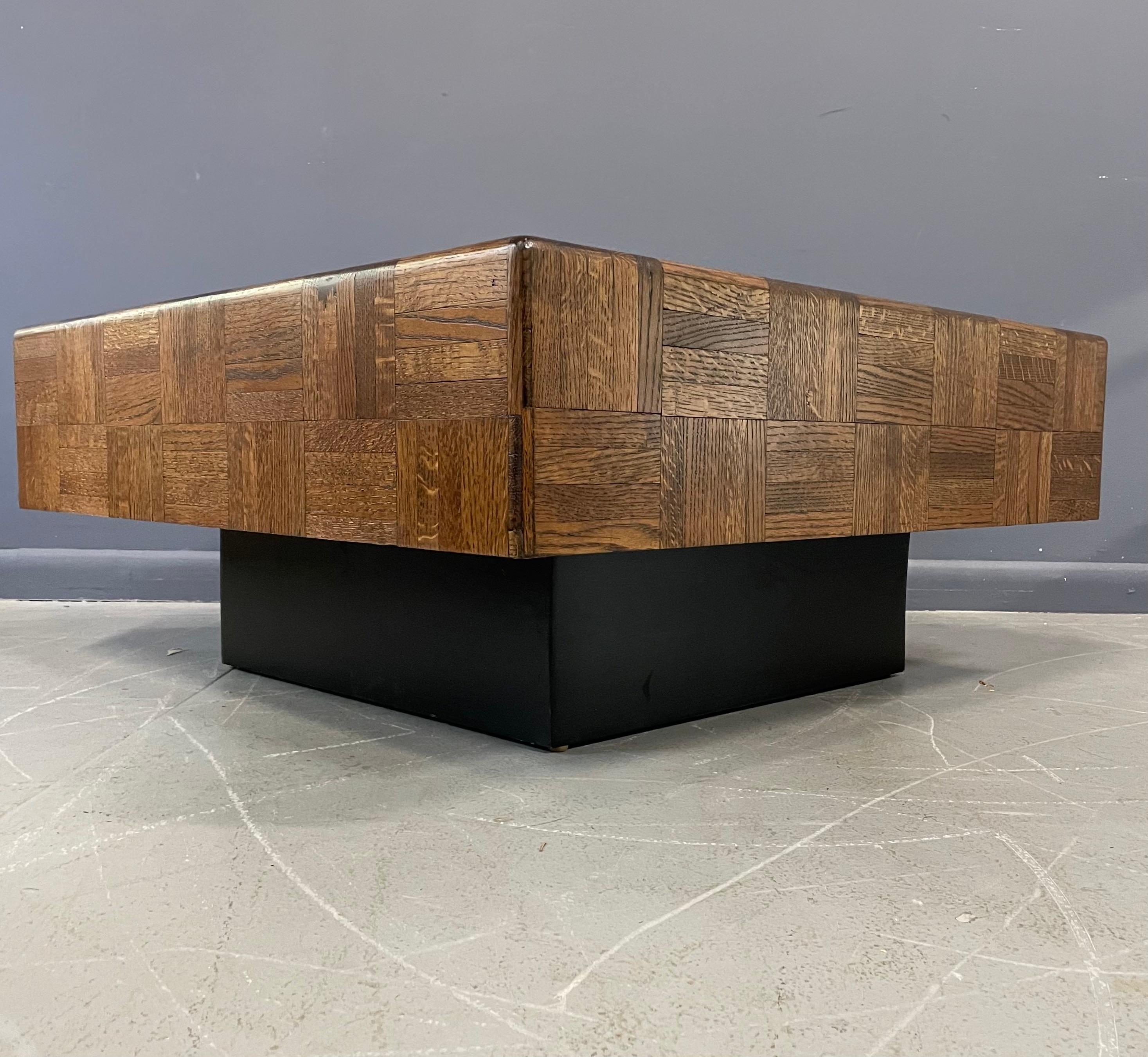Refinished coffee table with oak parquet in a coffee colored stain on a recessed black plinth base that gives the impression the table is floating.