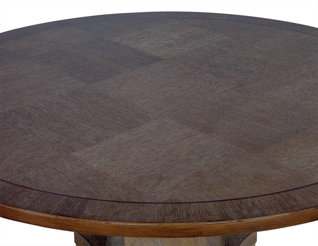 Round occasional table designed with a cerused oak veneered parquetry top, finished in a light brown with grey undertones. The top is raised on an empire inspired central pedestal. The interior core has been constructed with hardwood solids.
