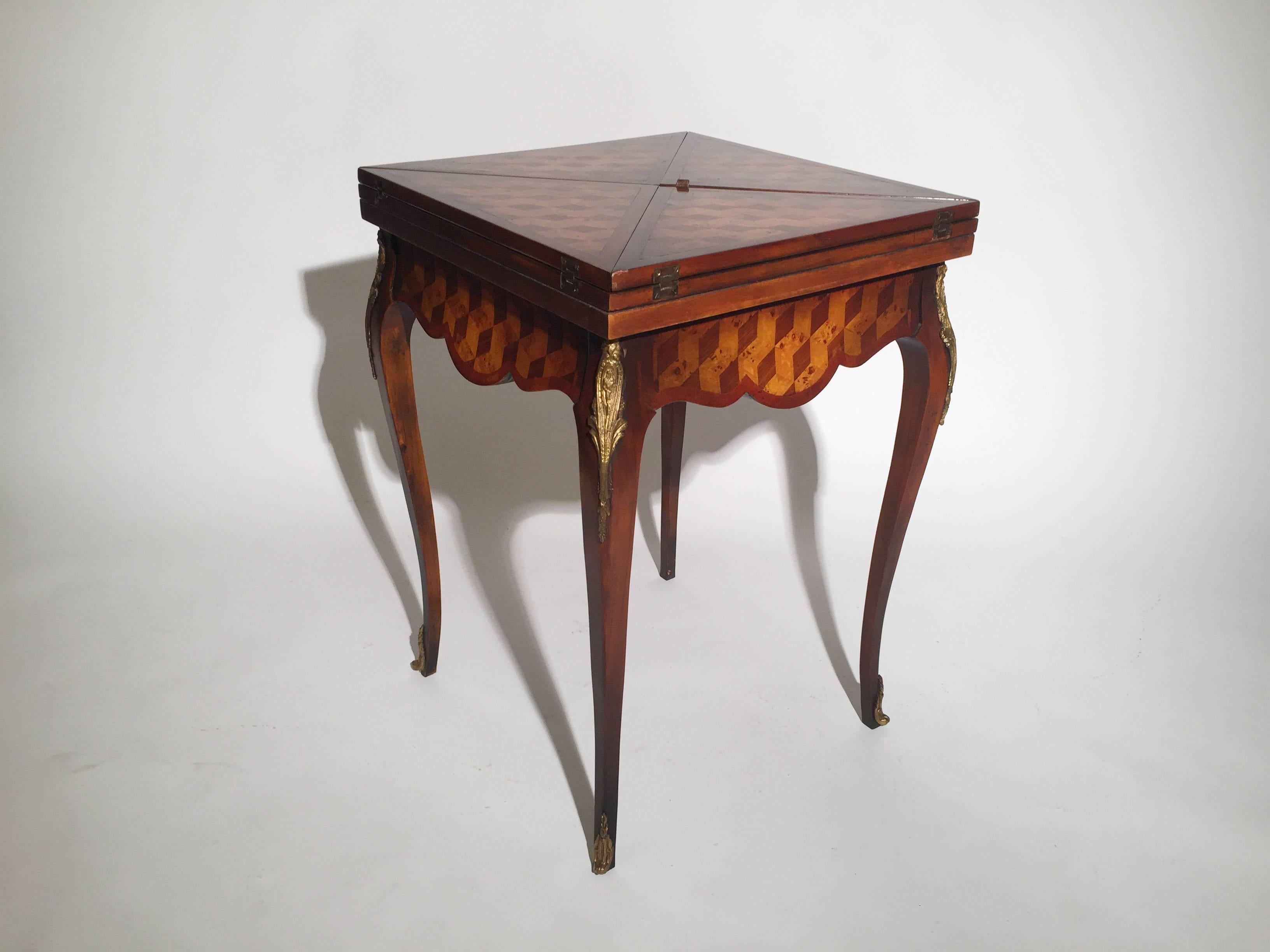 The table with four leaves that flip open to reveal a leather card playing surface and inlaid chess board. The apron concealing a single central drawer. The graceful curved legs with cast brass mounts. By Theodore Alexander in mahogany, and burl