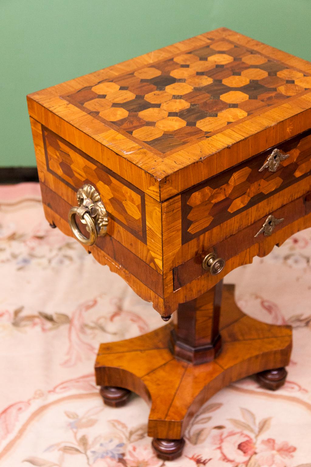Parquetry inlaid box on base, with crossbanded top, front and sides, the top with octagonal shapes in various exotic woods, front and sides with hexagonal shapes, single rosewood veneered drawer, oversize side ring pulls with floral back plates,