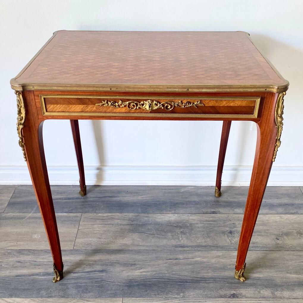 Our exceptional writing table in the Louis XVI style features fine parquetry inlay on top, drawer front with gilt bronze beading and rocaille mounts, and bronze mounts to the legs and sabot feet.  Well-crafted with hand-cut dovetails and original