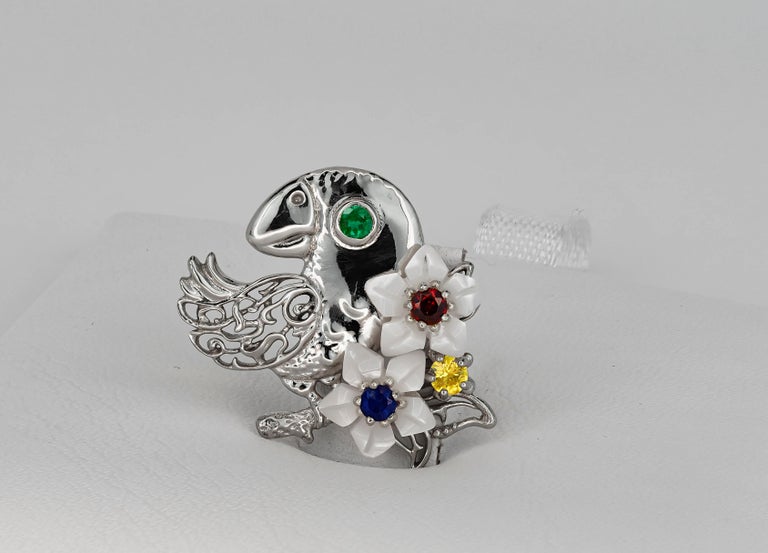 Parrot solid gold pendant with natural emerald, sapphires, ruby and mother of pearl carved flowers.
14 kt solid white gold 
Size: 18.9 x 23.2 mm.
Total weight: 2.40 g. (pure gold weight - 2.2 g.)

Natural gemstones:
Emerald: green color,
