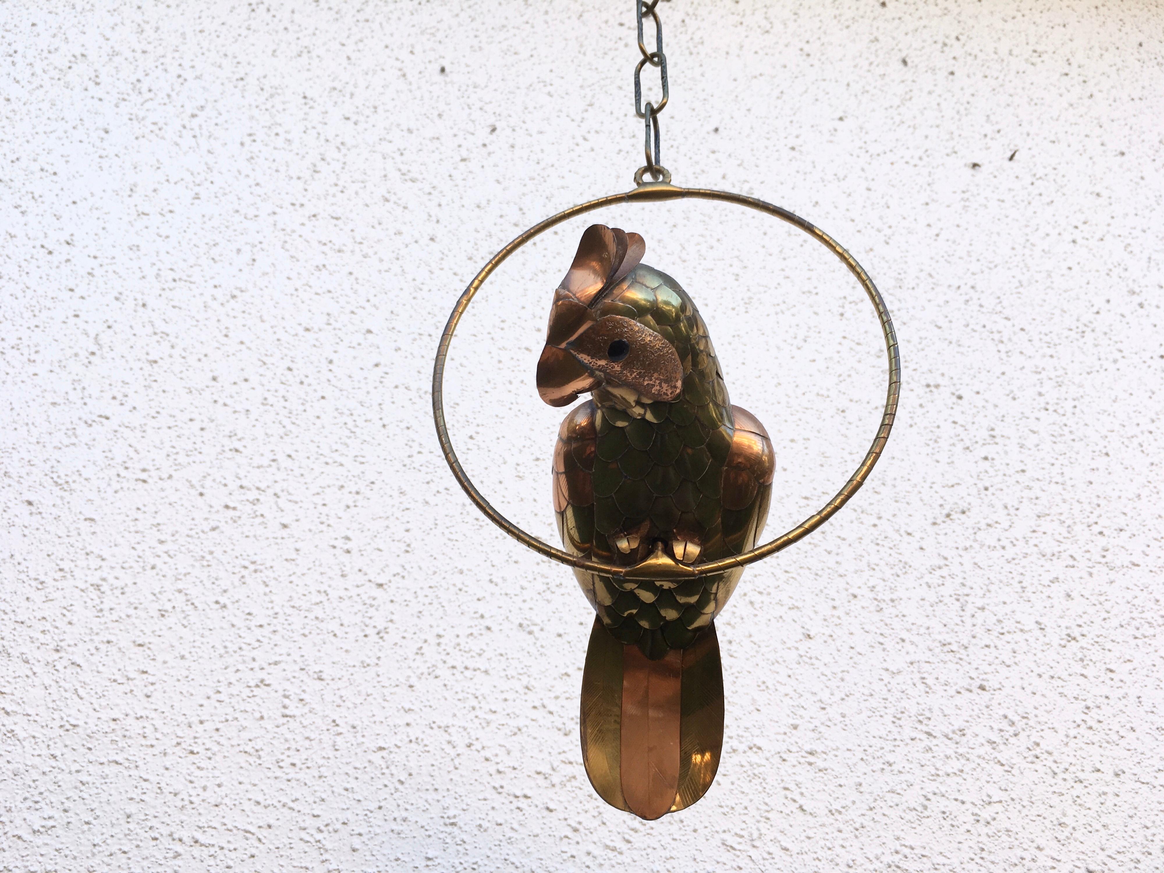 Brass and cooper parrot on swing with chain by Sergio Bustamante.
Chain has only four links. Dimension provided include ring.