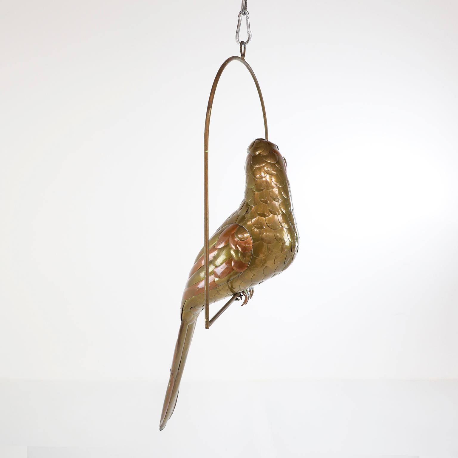 Copper, brass and aluminium Parrot on a hoop hanging stand by Sergio Bustamante, circa 1960. presents some damage to the head and tail.

Sergio Bustamante is a Mexican Artist and sculptor. He began with paintings and papier mache figures,