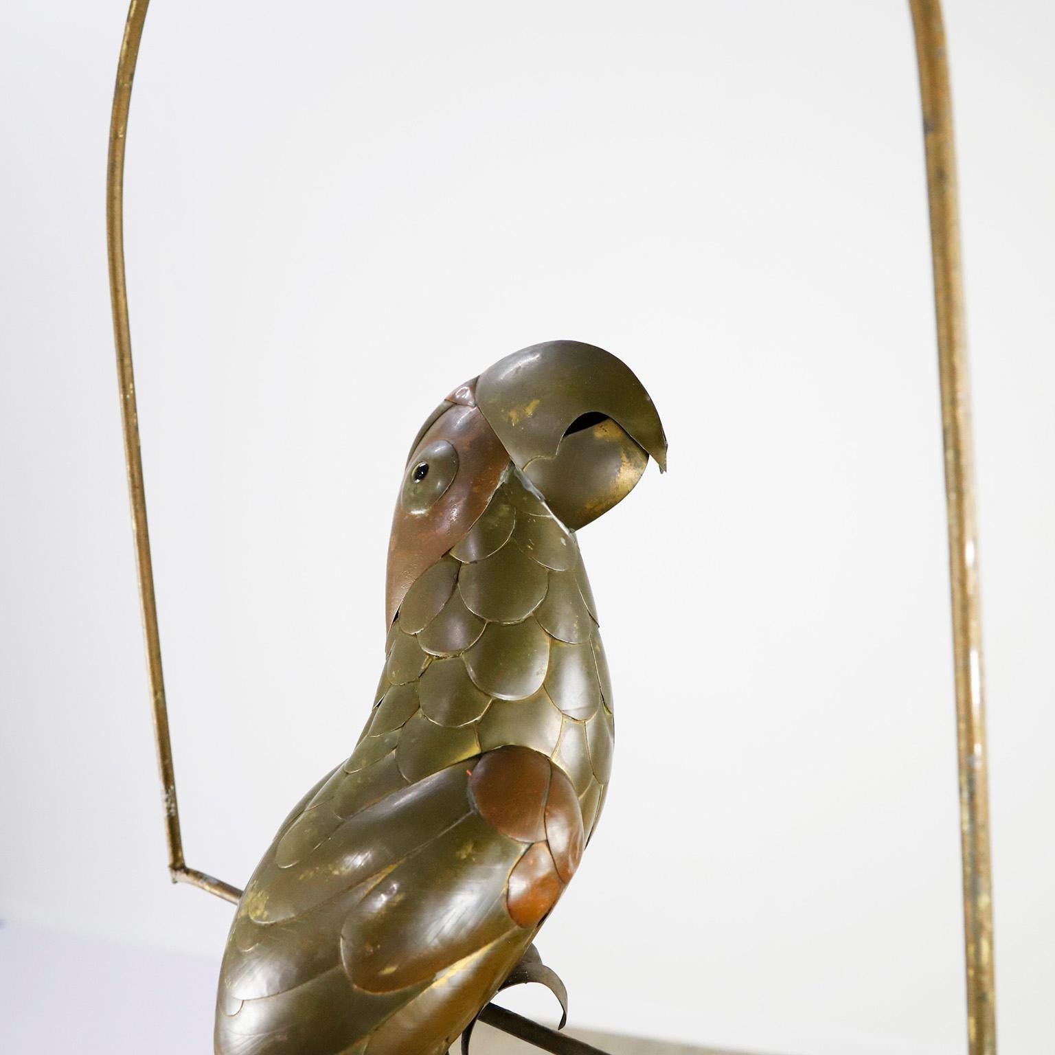 Copper, brass and aluminium Parrot on a hoop hanging stand by Sergio Bustamante, circa 1960. presents some damage to the head and tail.

Sergio Bustamante is a Mexican Artist and sculptor. He began with paintings and papier mache figures,