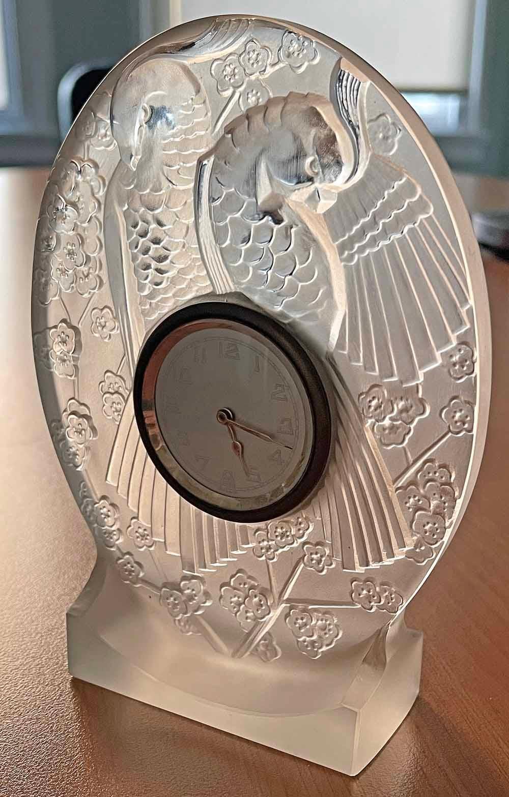 Virtually glowing as light passes through its satiny glass, this highly rare Art Deco clock by Maurice Model features two parrots grooming their feathers amidst a profusion of flowering branches.  Of all the artists and makers in France who