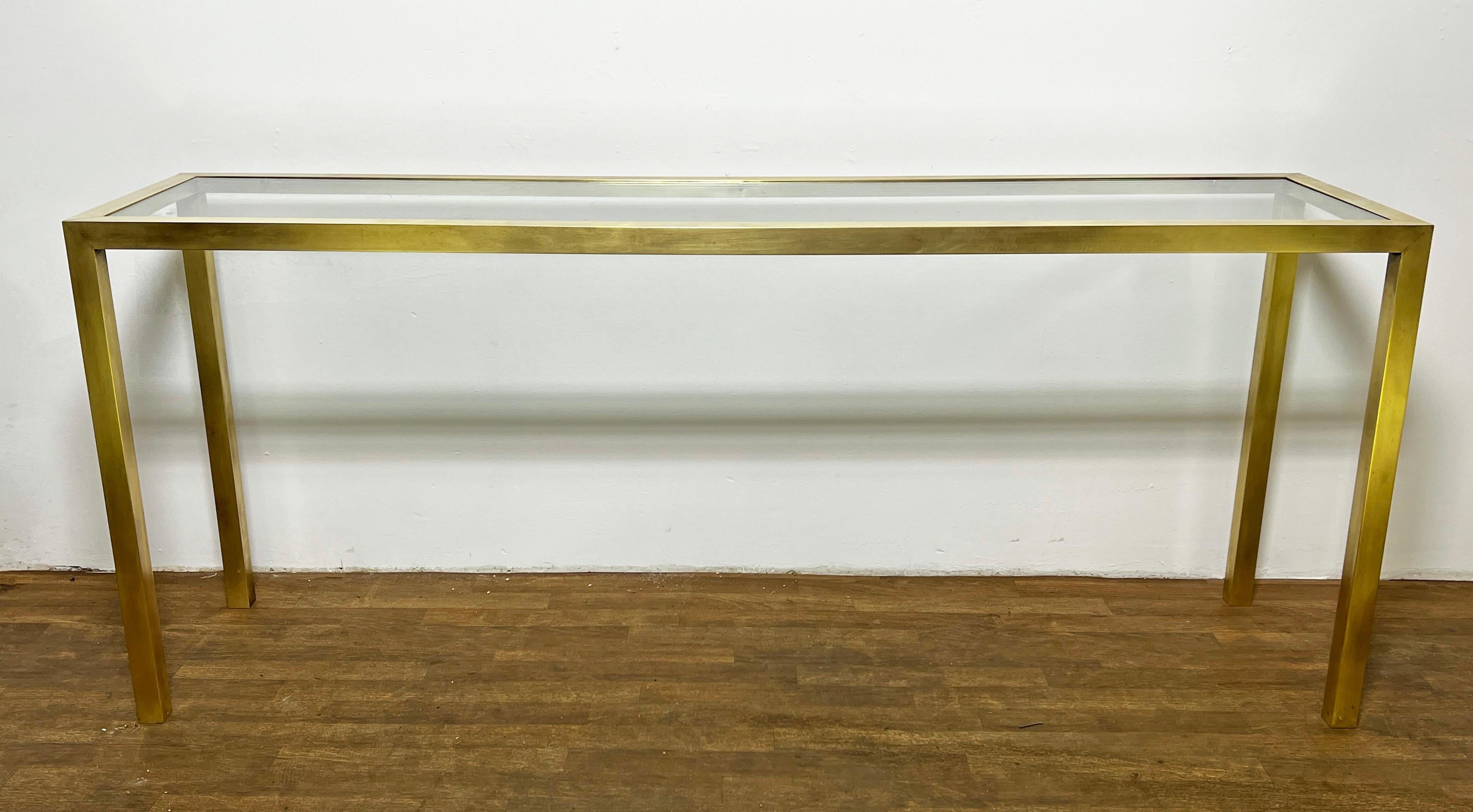 Brass parson's style six foot long console or sofa table with inset glass top attributed to Directional, circa 1970s.
