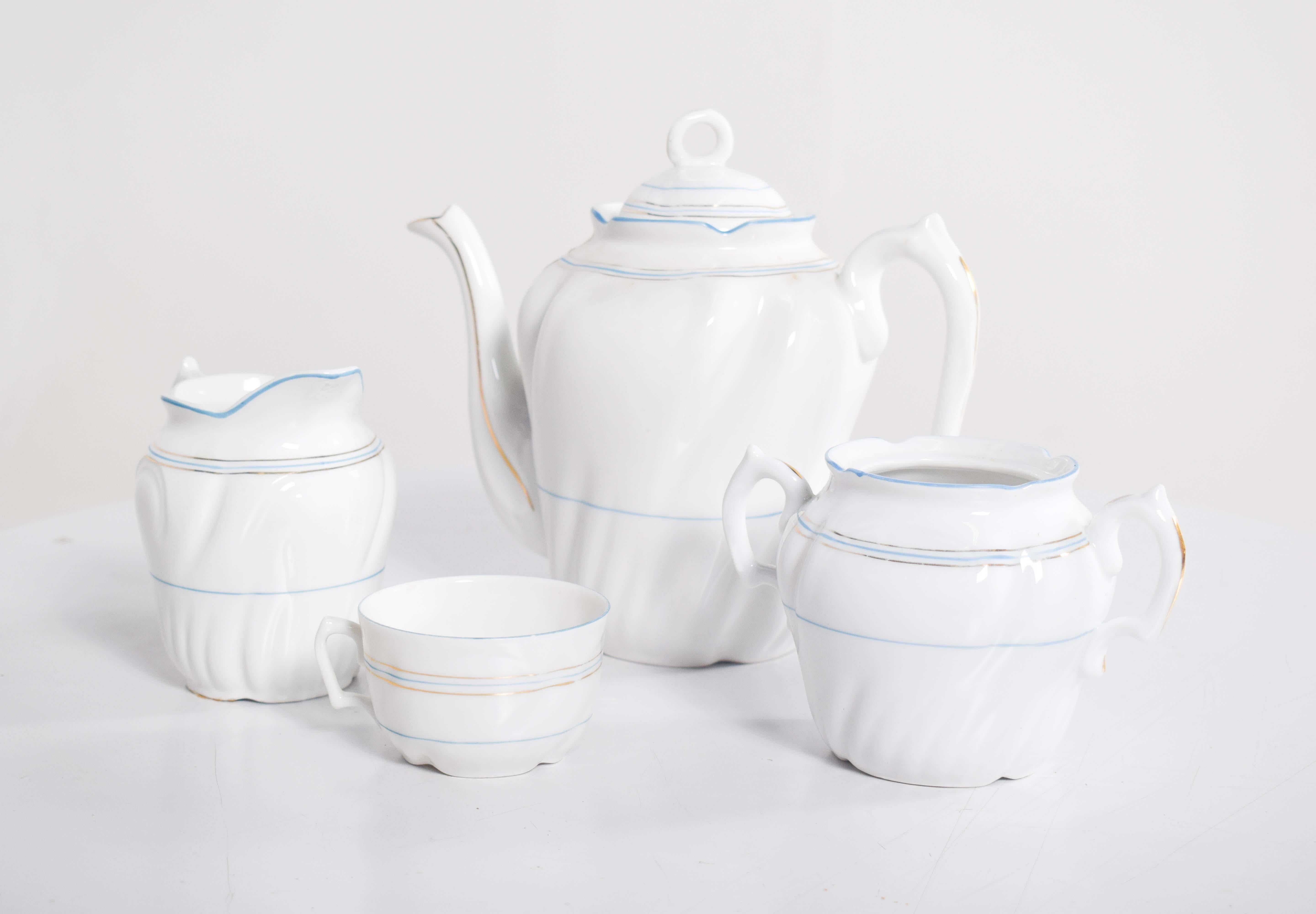 Questo raffinato servizio da tè, realizzato in porcellana Vista Alegre di alta qualità, presenta un sofisticato design bicolore con accenti azzurri ed eleganti finiture dorate. Il set comprende una teiera, una lattiera, una zuccheriera e una tazza