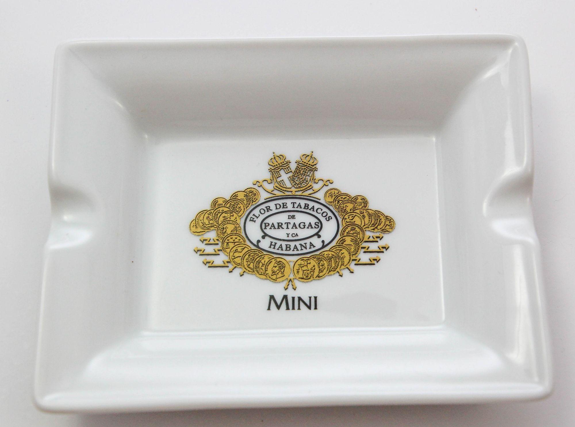 Partagás Porcelain Cigar Ashtray Dish Collectible 1960s.
Small white and gold advertising ashtray dish with the gold logo of Partagas cigars, the double crown, gold pieces of money and the script: Flor de Tabacos de Partagas Havana.
Use it as an