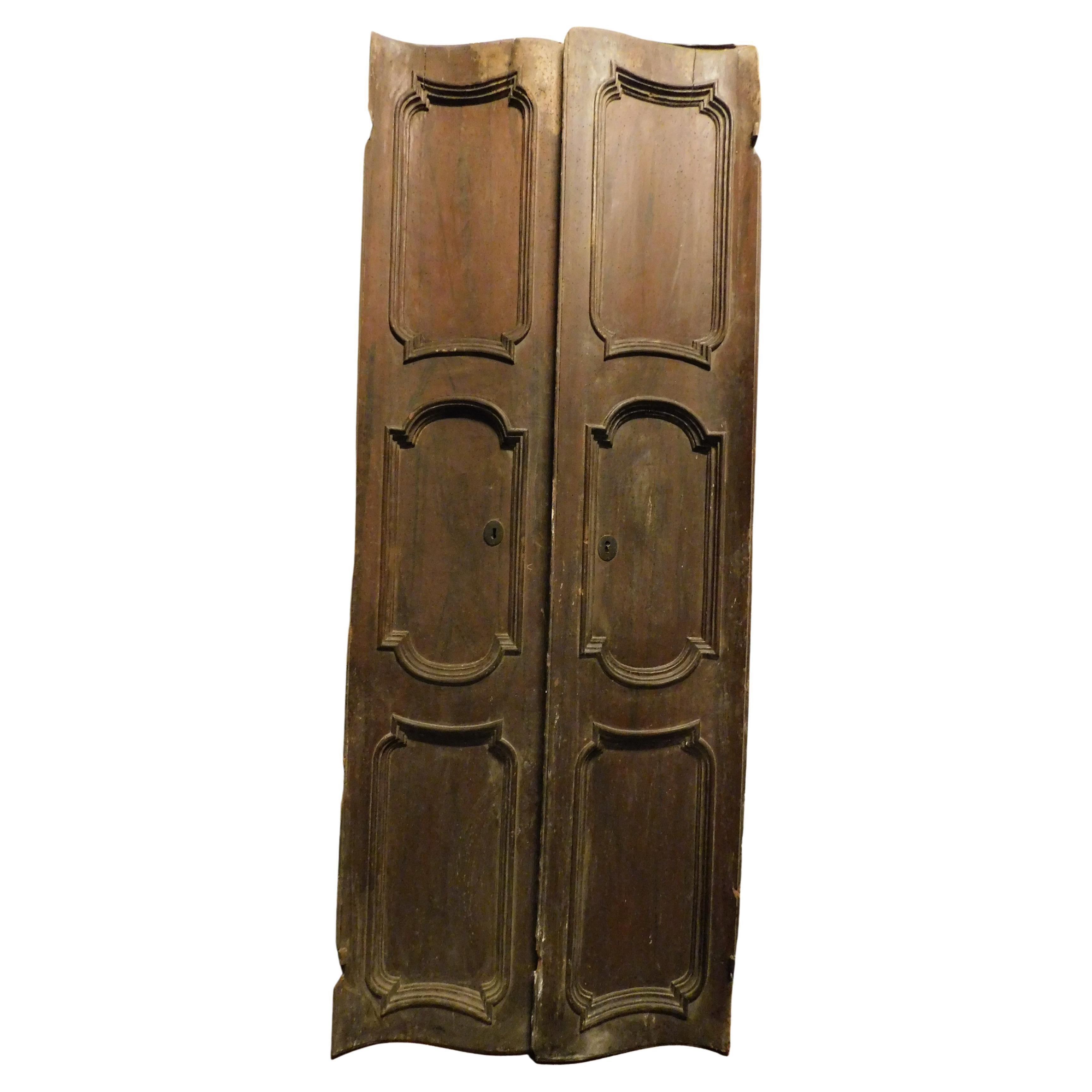 Puerta particular de nogal, de doble batiente con dos hojas y paneles tallados, Italia