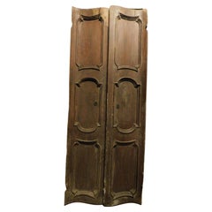 Puerta particular de nogal, de doble batiente con dos hojas y paneles tallados, Italia