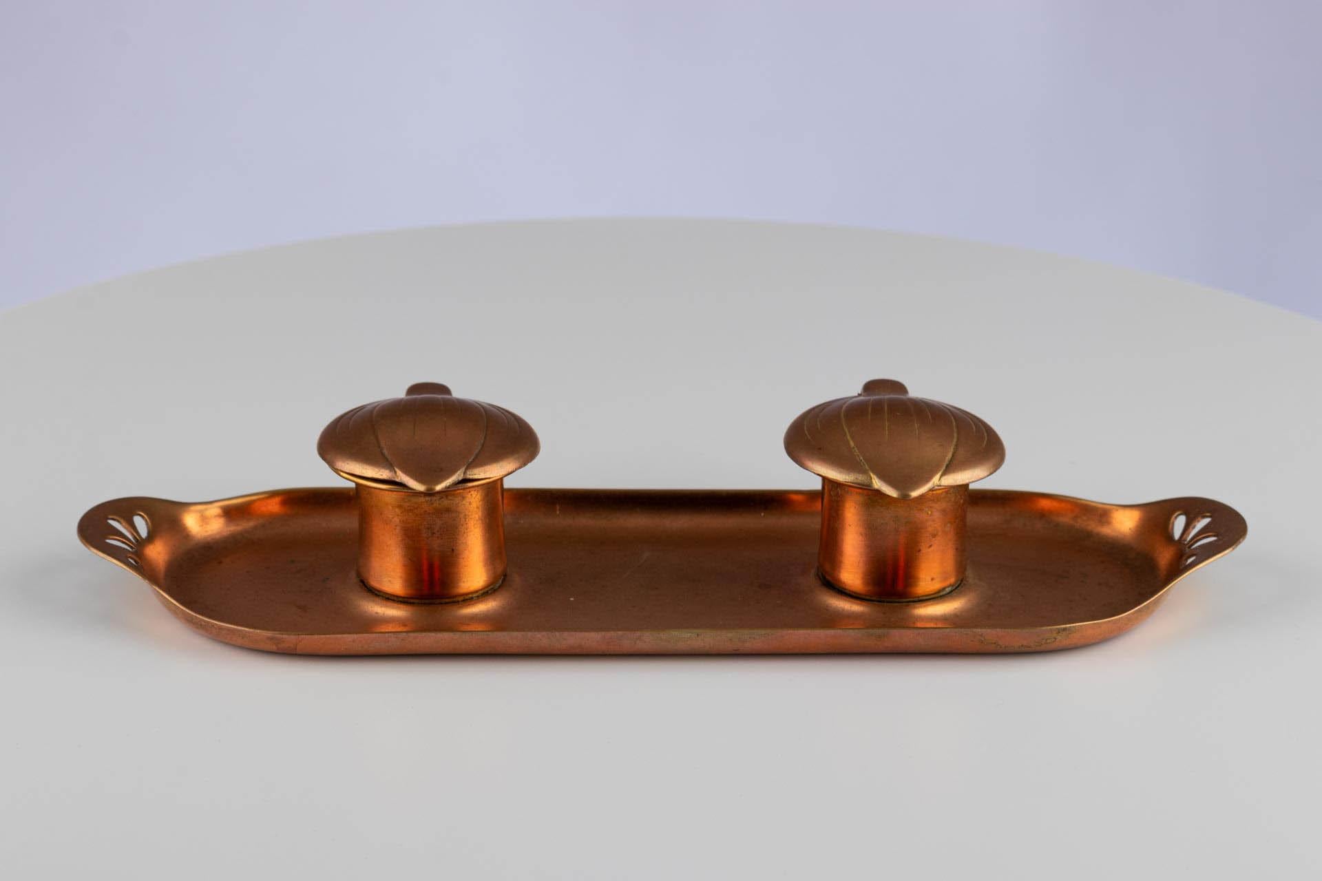 Encrier Art Nouveau avec couvercles en forme de feuilles

Origine : Allemagne
Matériau : Cuivre avec encriers en porcelaine
Date : Circa 1900

Description :
Encrier rectangulaire en cuivre aux côtés légèrement incurvés et aux poignées découpées