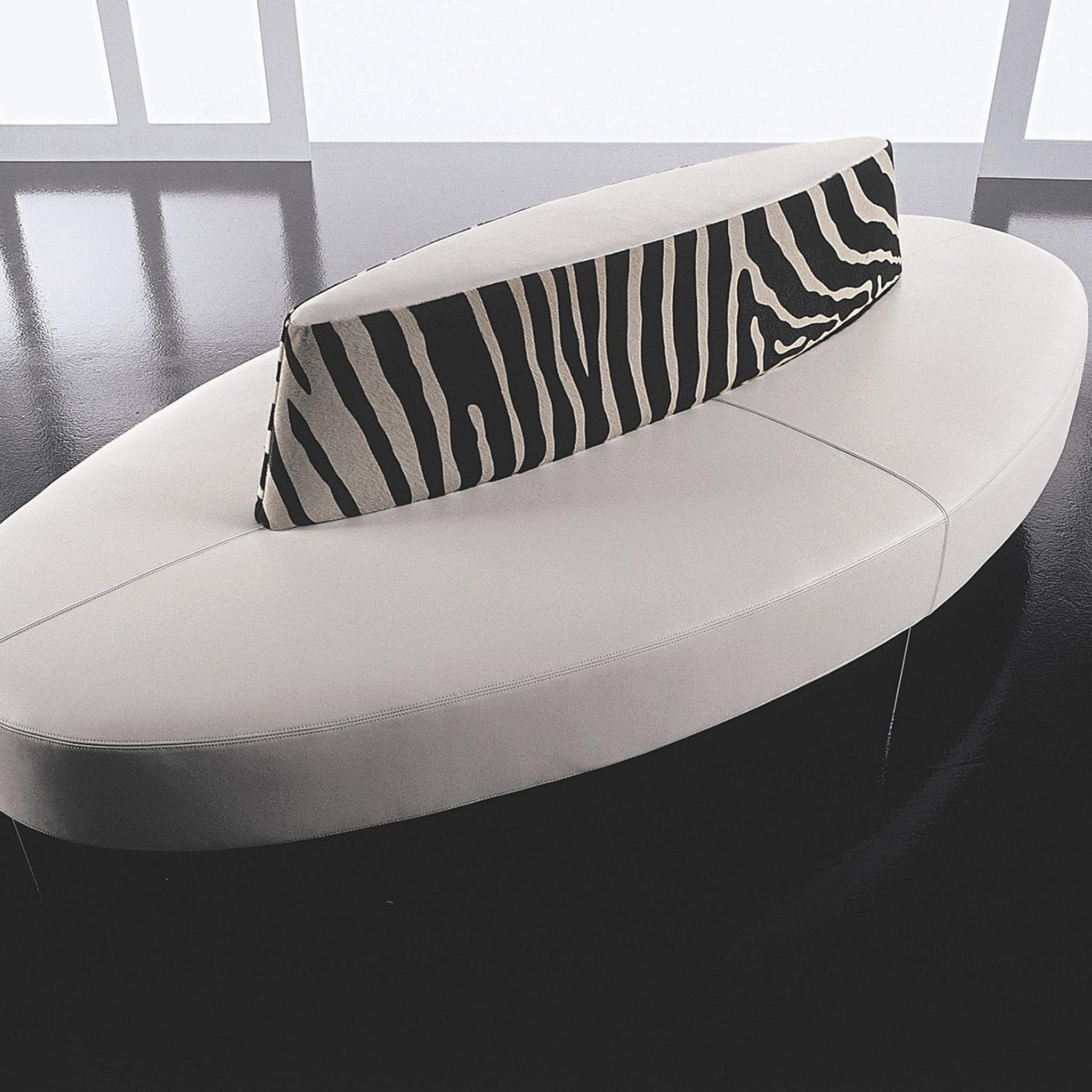 Reminiscent of the pop-art styles of the 1960s, this sleek, modern, elliptical-shaped sofa features stainless steel legs and a supporting frame in beech plywood. Its padded seat is covered in white, genuine leather, while zebra-striped, pony-hair