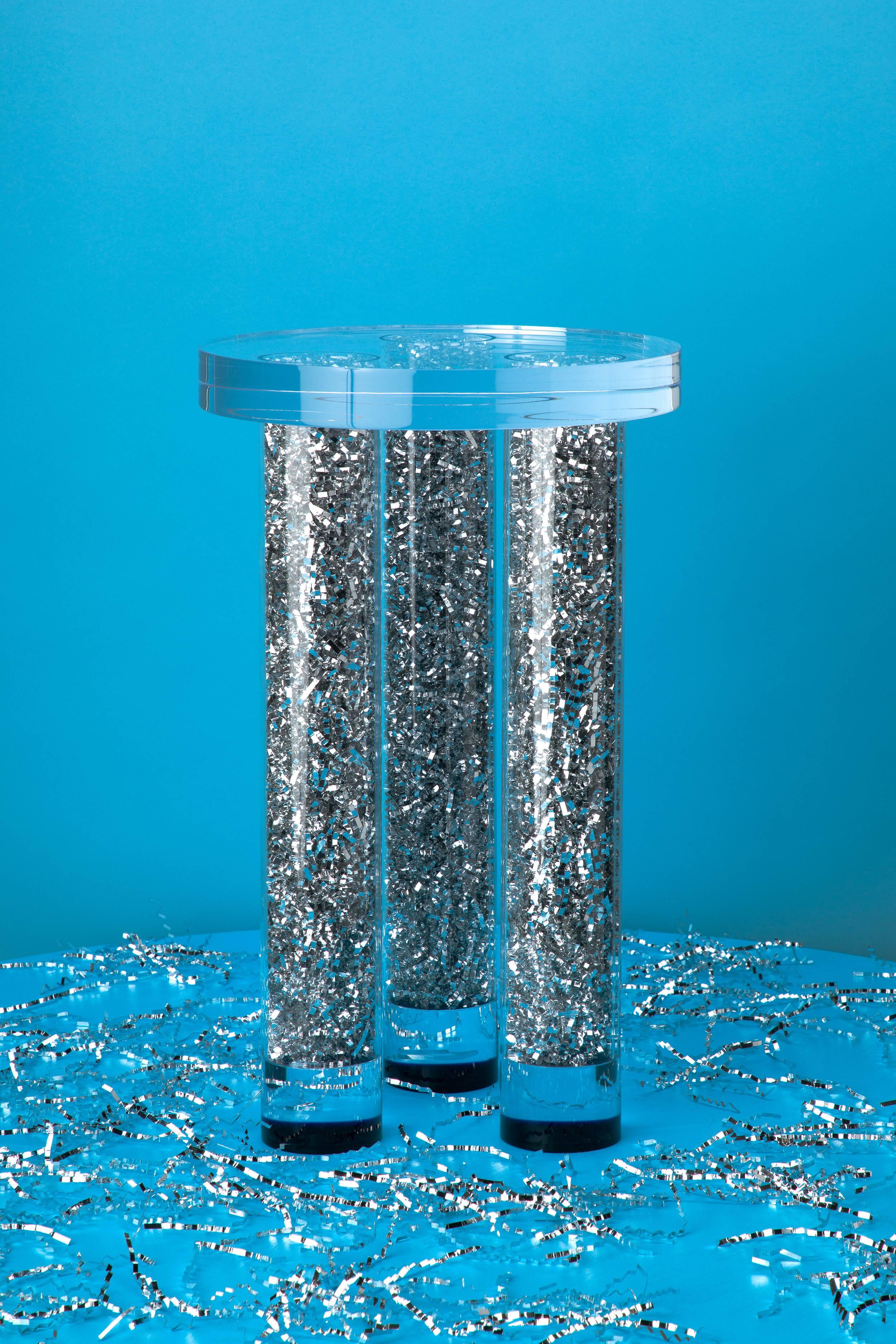 With the Party On Table, the party never has to stop. The table features a chunky clear acrylic top supported by acrylic tube legs that have been stuffed with silver metallic crinkle paper - a material that is often used for table decoration at