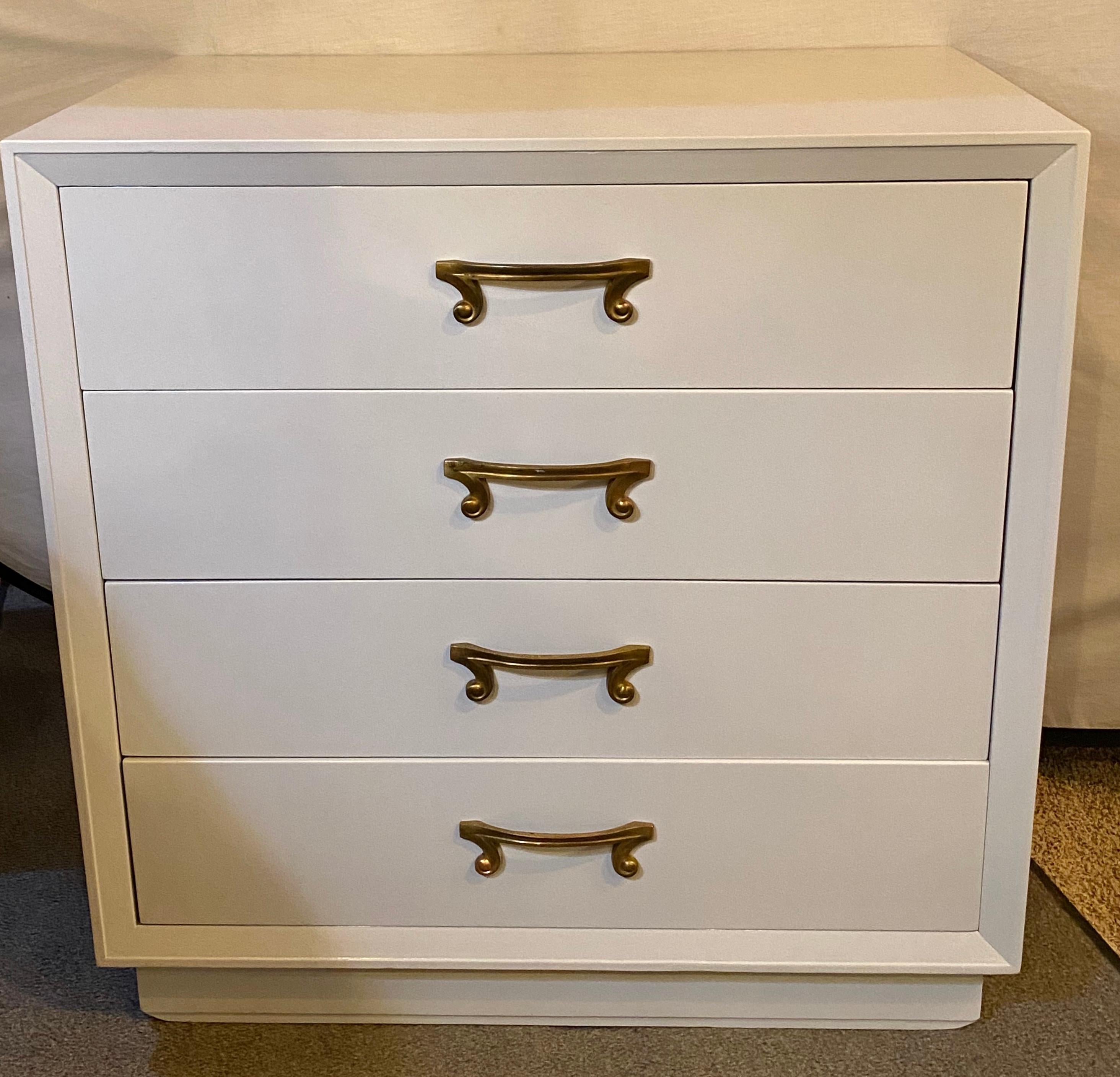 Parzinger style Hollywood Regency four-drawer chest dresser commode dove grey lacquer. This finely designed chest has recently been fully redone in a dove gray lacquered finish. The Tommi Parzinger style commode or bedside stand has gilt metal