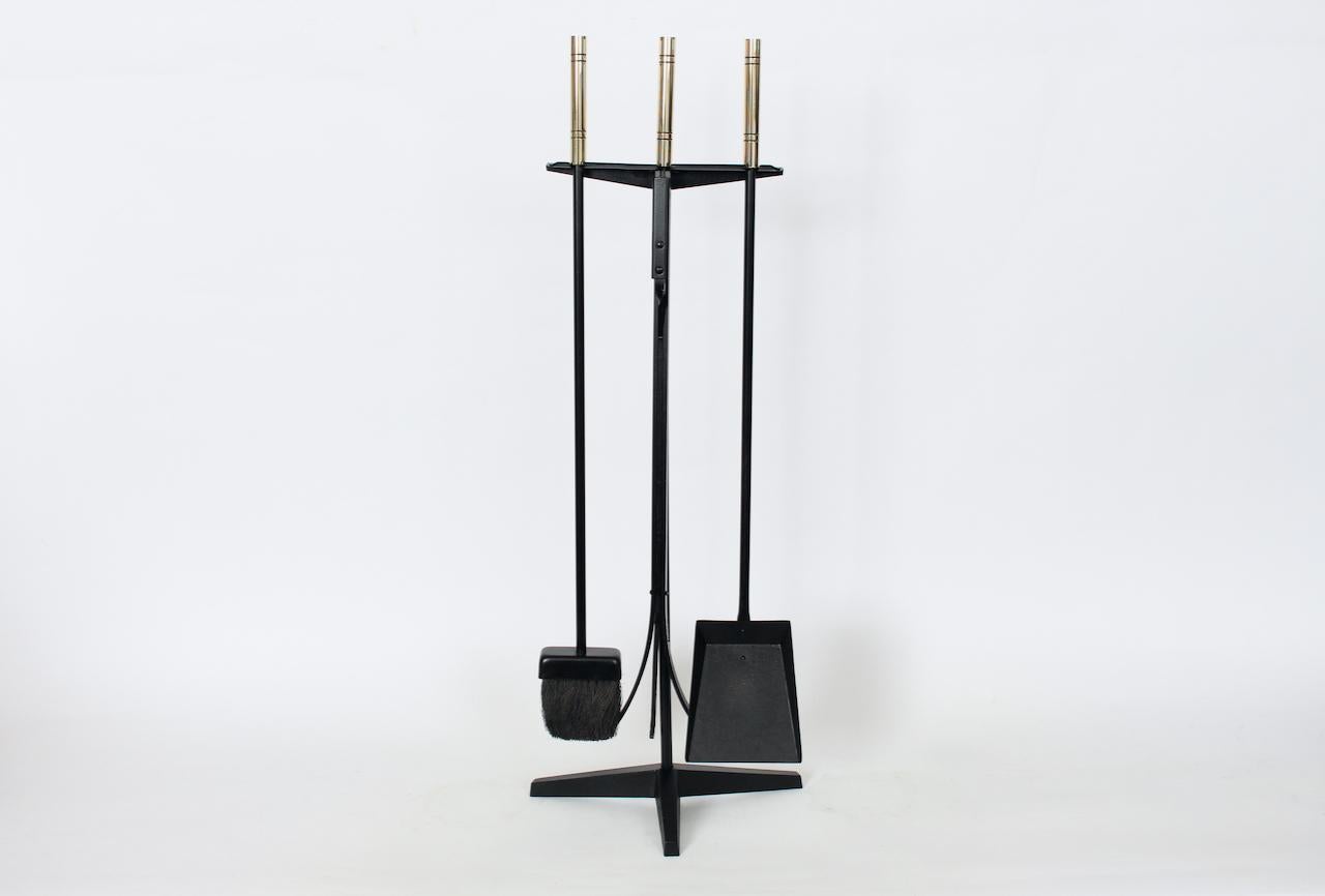 Three Piece Fireplace Tool Utensil Set in Cast Iron and Brass, Circa 1960.  Featuring a heavy 3 piece tool set with 3 matte Black enameled wrought iron and brass handled tools. With Broom, Shovel / Dust Pan, adjustable Flextong Claw Poker, each with