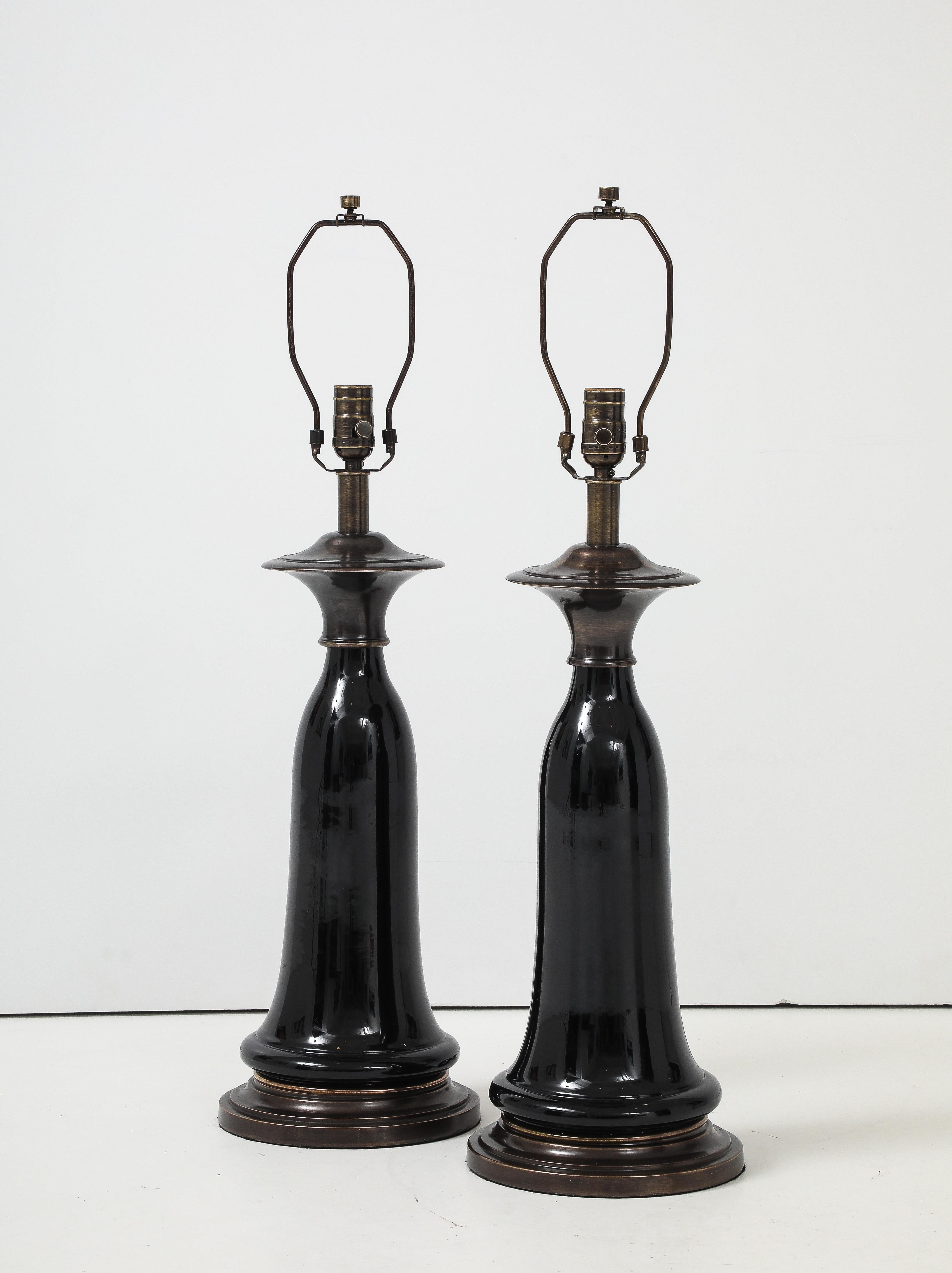 Paire de lampes en porcelaine noire en forme de cloche stylisée sur des bases en bronze finies sur mesure. Les lampes ont été recâblées de manière professionnelle avec des cordons en tissu noir et des douilles robustes. Ampoules de 100W, une