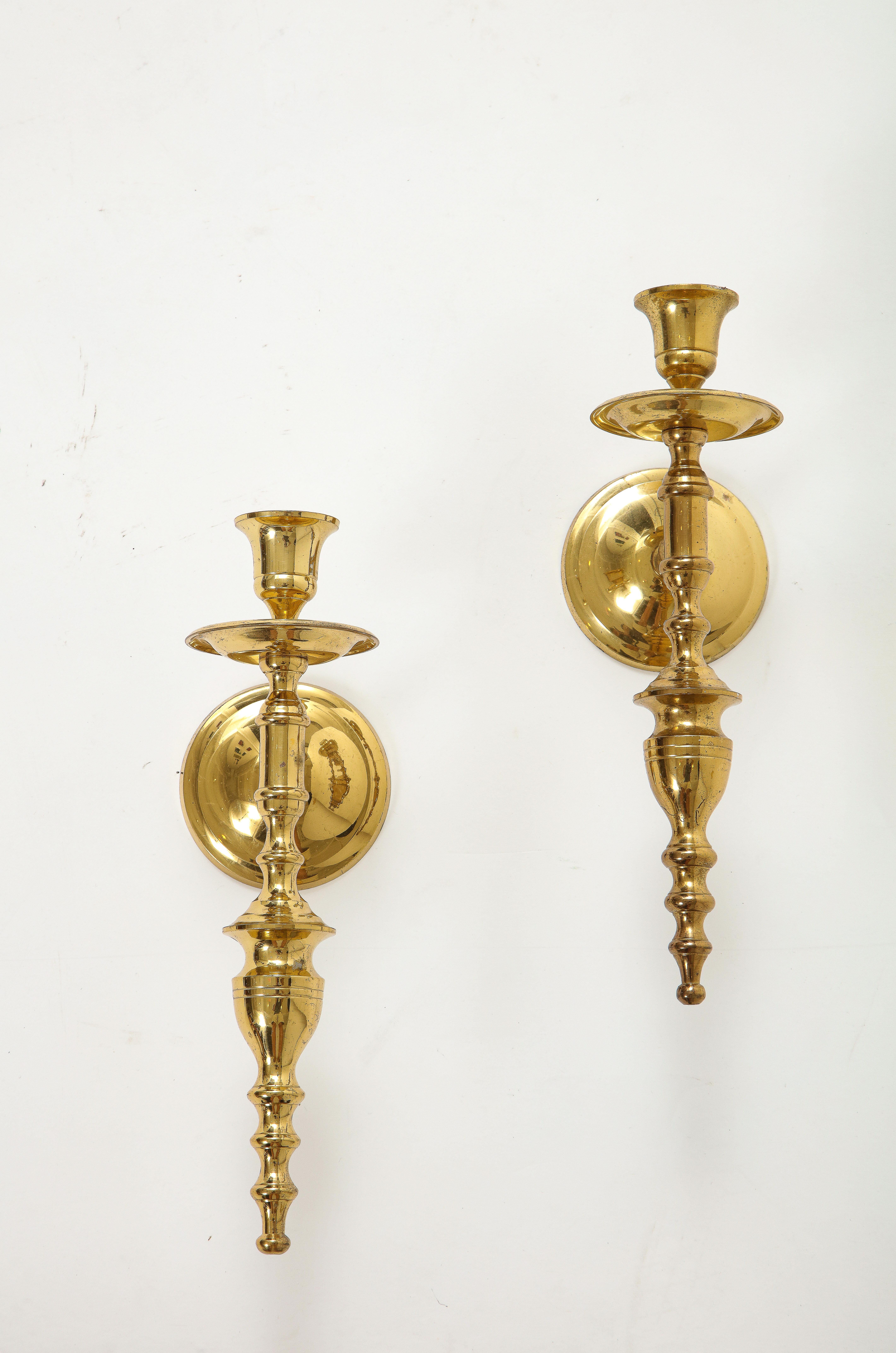 Pair of Hollywood Regenbcy sold brass sconces with a Tommi Parzinger influence. Brass backplate measures 3 3/8 inches in diameter.