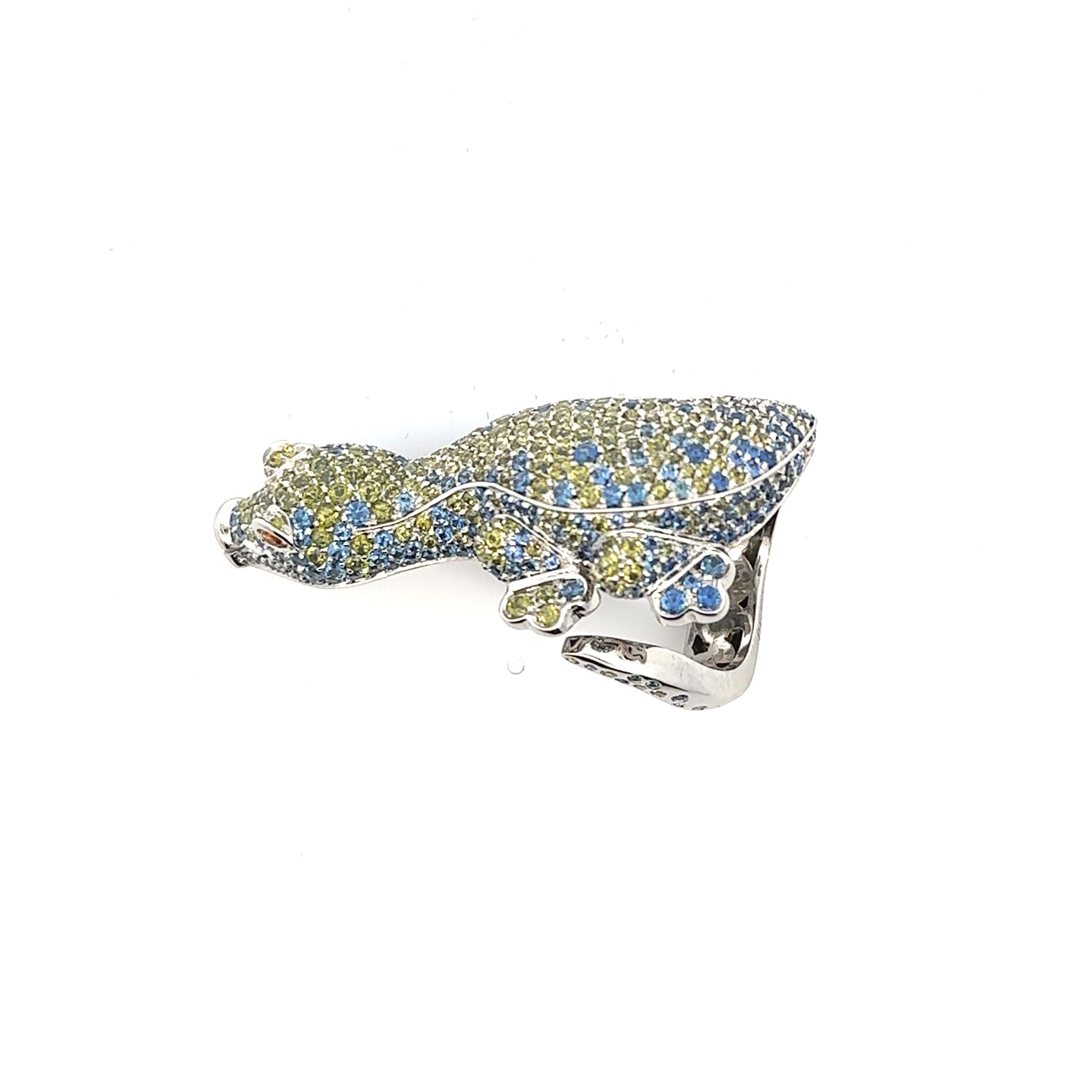 Introducing the rare and stylish Pasquale Bruni Crocodile Ring. Crafted with utmost precision, this masterpiece showcases a mesmerizing crocodile design, its body adorned with a luxurious pavé setting of circular-cut sapphires and green topaz,