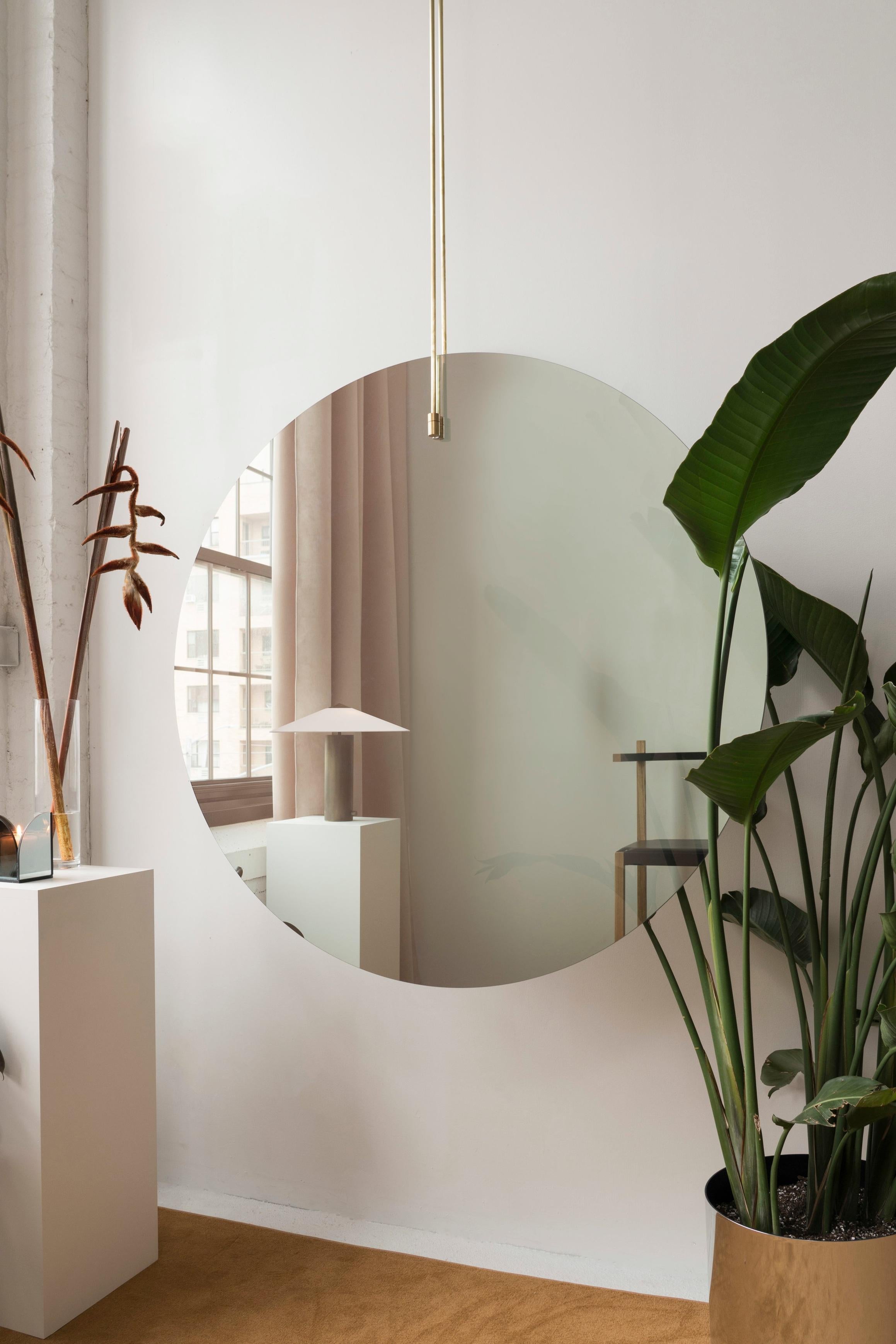 This is dramatic and bold mirror is intended to be used either as a focal point in front of a wall or window or as a sculptural room divider. Suspended from the ceiling by brushed-brass rods, it is made of one-way mirror - one side offers a slightly