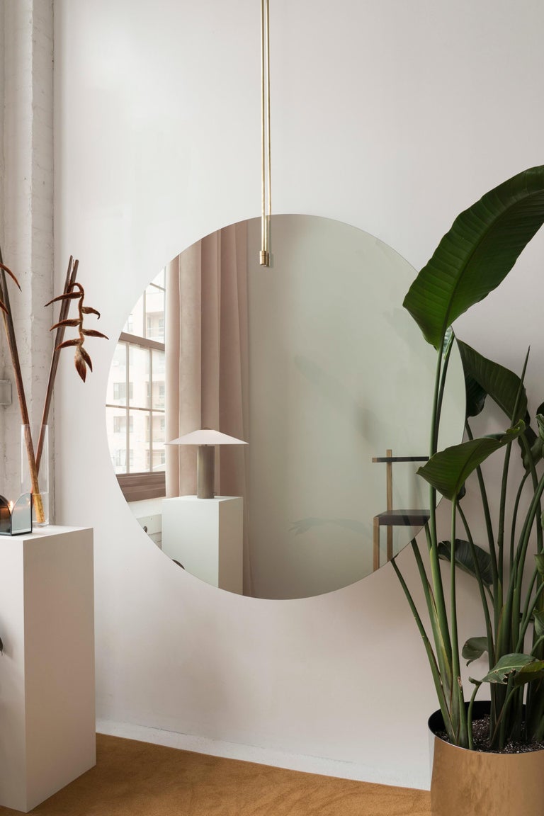 This is dramatic and bold mirror is intended to be used either as a focal point in front of a wall or window or as a sculptural room divider. Suspended from the ceiling by brushed-brass rods, it is made of one-way mirror - one side offers a slightly