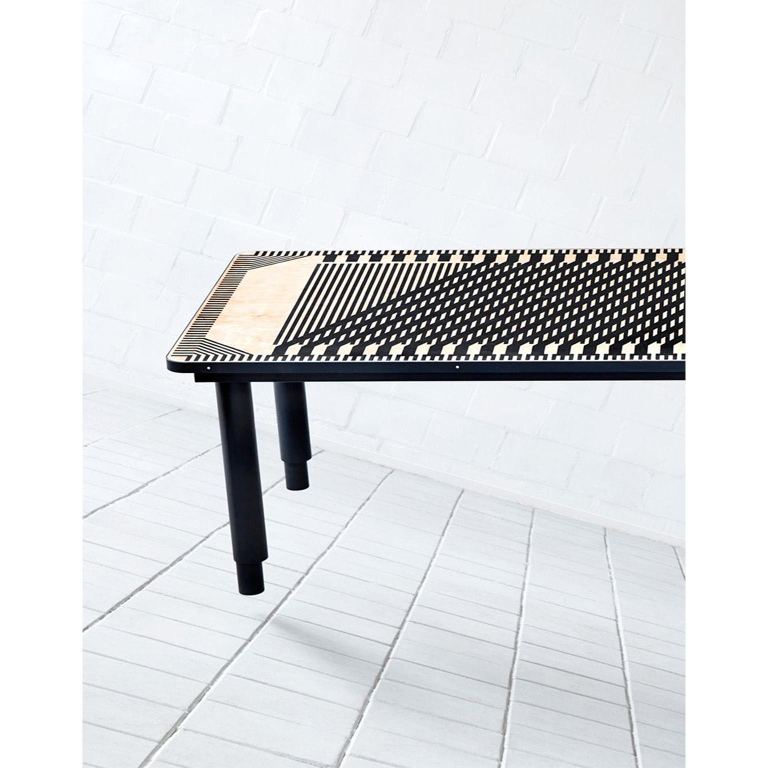 The intricate pattern and design of ‘Passage Table’ consists of a wooden inlayed, graphical pattern, and is finished with a smooth satin gloss. The table is supported by solid, metal legs with a-centric feet resulting in a slightly lighter base that