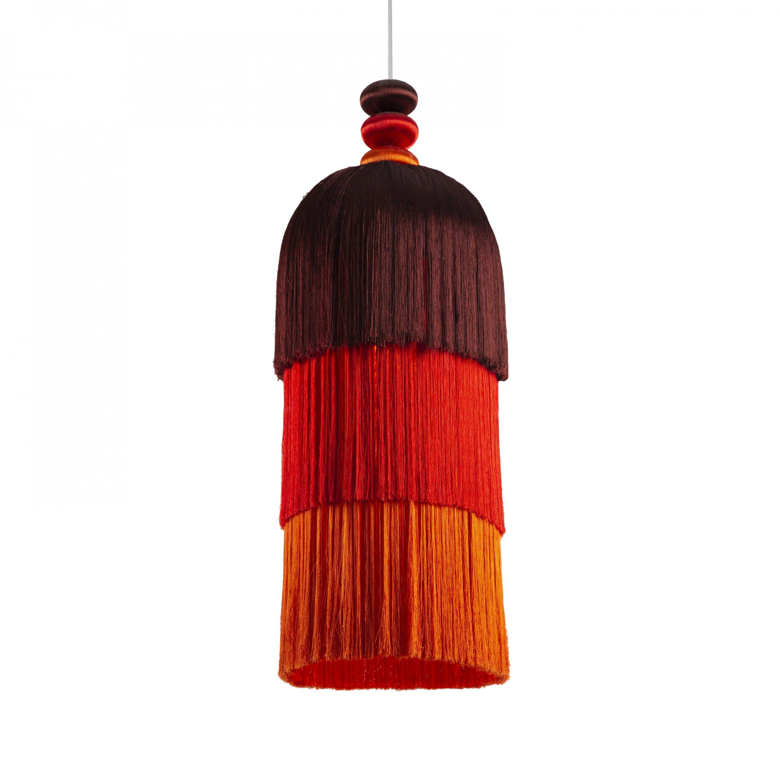 Questa lampada a sospensione artigianale è una gioiosa celebrazione del colore, della struttura e del movimento. Il primo progetto illuminotecnico di Shewekar fa rivivere l'antica arte della passementerie, un mestiere tradizionale che consiste