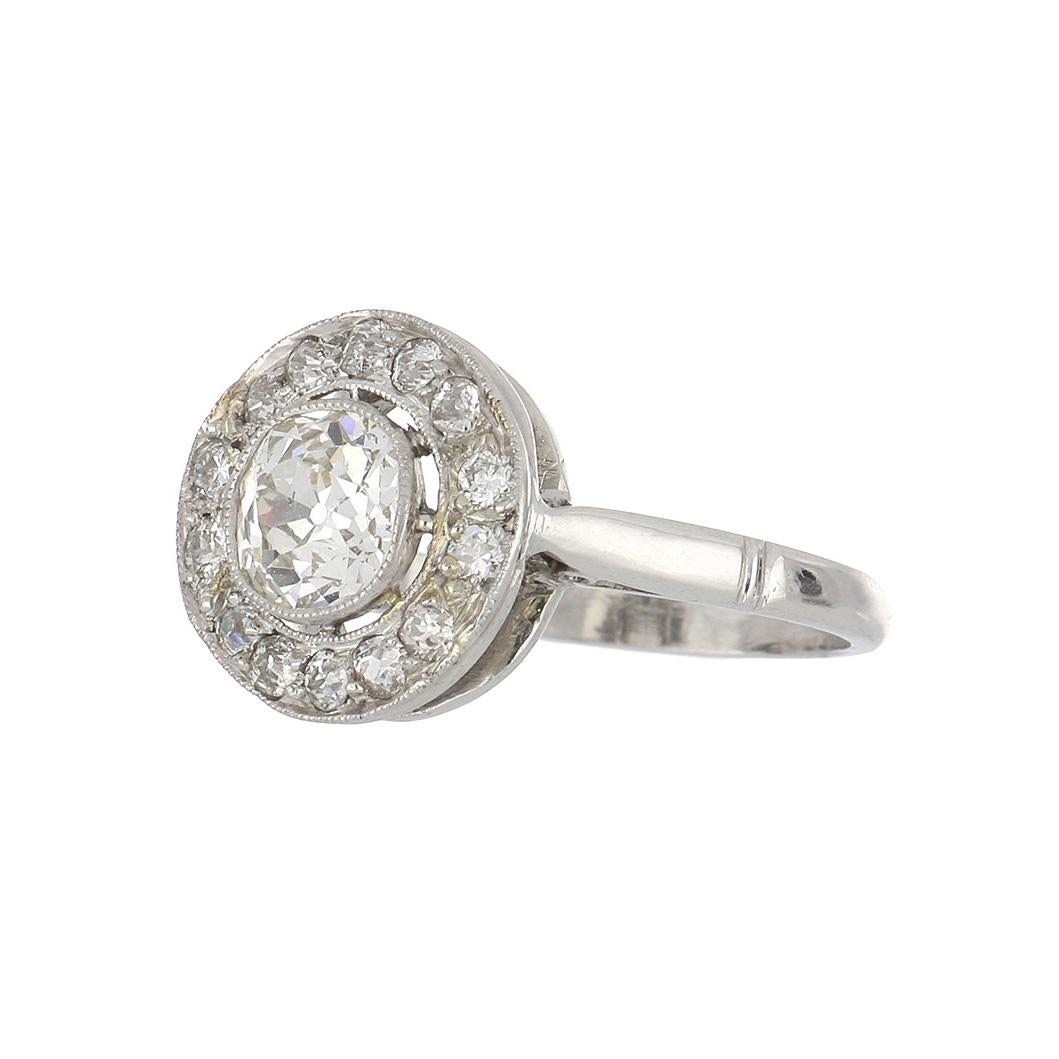 An Edwardian platinum and diamond cluster ring, featuring a central diamond framed by smaller bead-set diamonds, circa 1915.

Ring contains one Old Mine-cut diamond (total weight of 0.93 carat, color: J  clarity: SI1)  and 14 Old European-cut
