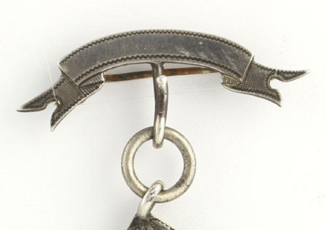 Dieser alte Freimaurerschmuck zeigt ein großes Quadrat, unter dem ein Satz des Pythagoras hängt.  Das Quadrat wird durch eine blattähnliche Umrandung akzentuiert und hat eine glatte, niedrig polierte Oberfläche in der Mitte.  Der Satz des Pythagoras