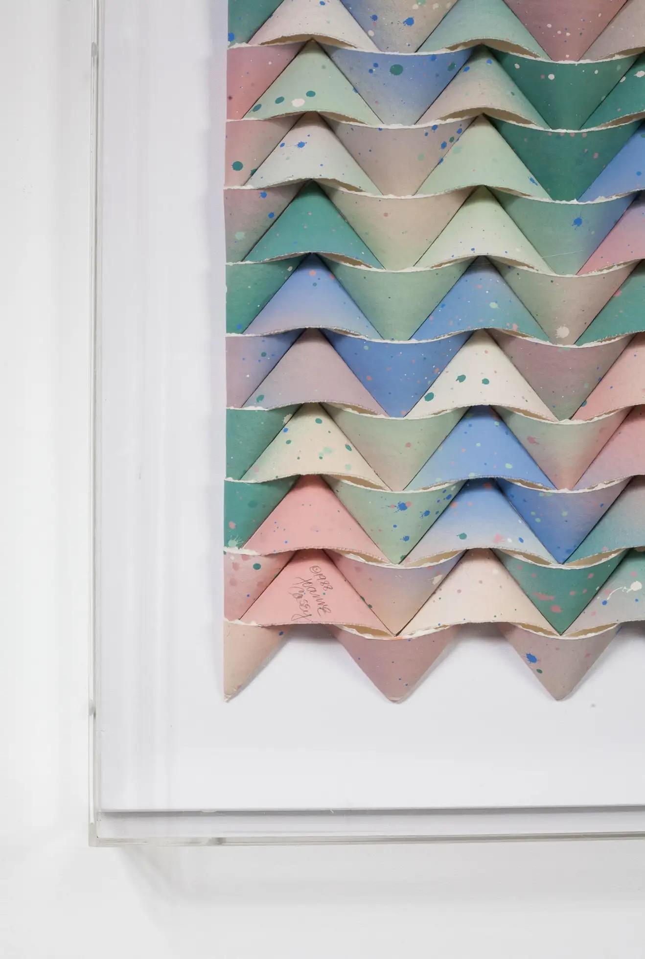 Contemporary French artist Joanne Casey paper abstract.
Rows of strips of pastel colored paper folded in undulating chevron pattern.
Strips are placed in opposite direction to create a more 3D effect.
Framed in lucite box.
Signed by the