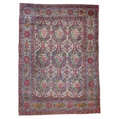 Tapis ancien botanique classique aux teintes pastel, vers les années 1940-1950