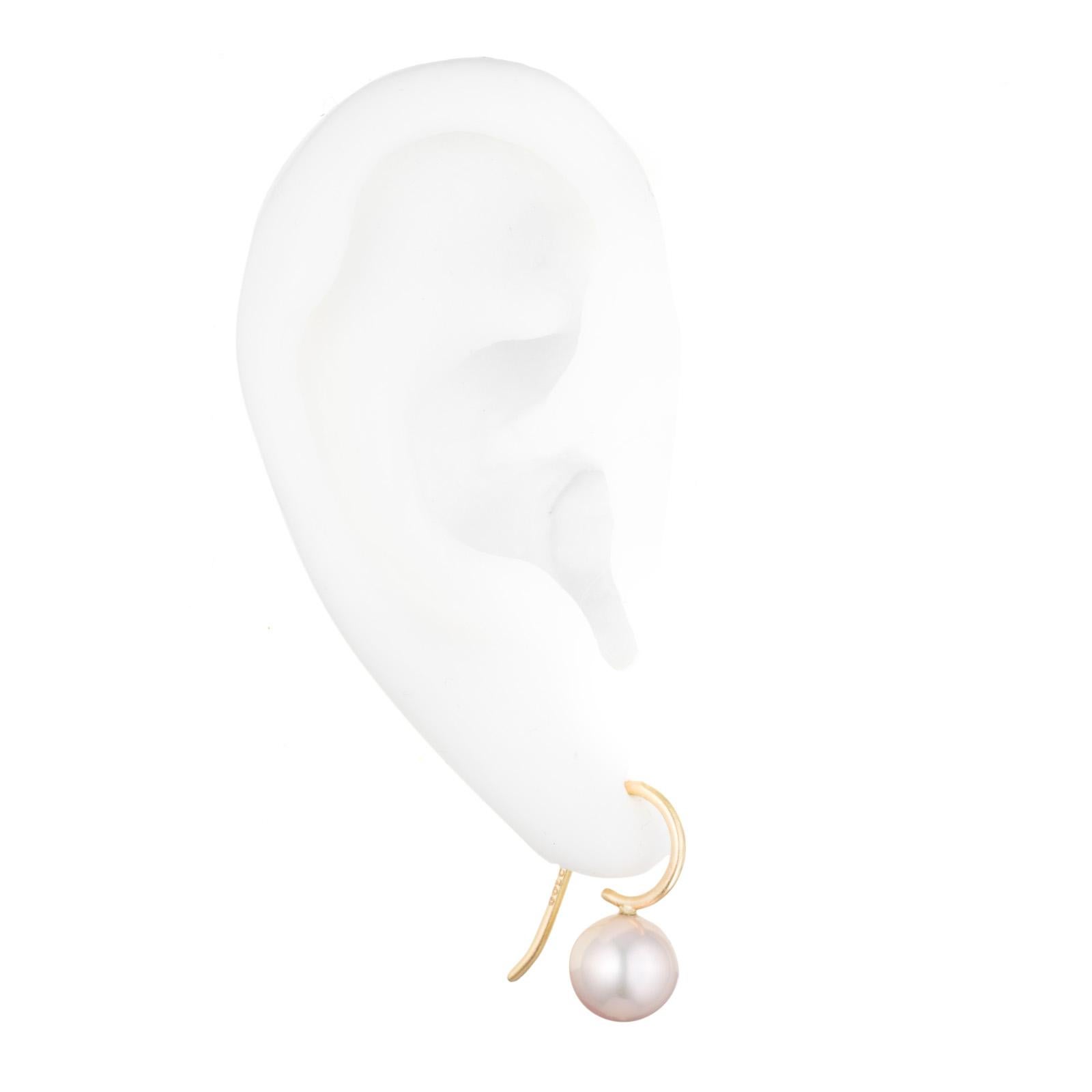 Our signature earrings with round pale pinkish peach round freshwater cultured pearls suspended from 18K gold ear wires. Everyone looks good in these and we use pastel peach & pink colored pearls because they warm up the complexion. Think blush, but