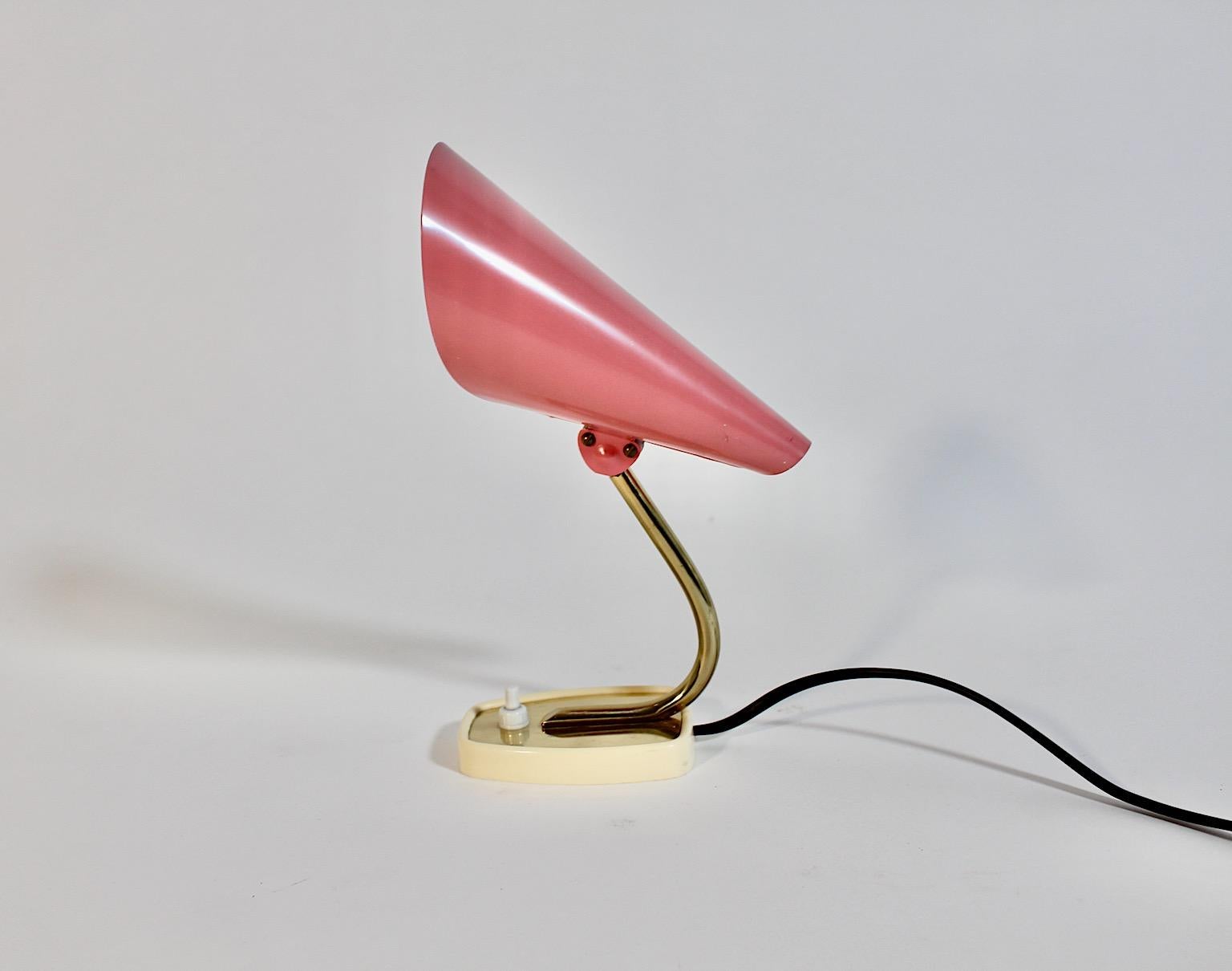 Mid Century Modern style vintage table lamp nightstand lamp or sconce from metal and plastic in pastel pink and golden color tones Italy.
An amazing table lamp from golden metal with a pastel pink lamp shade cone like with a rectangular base. The