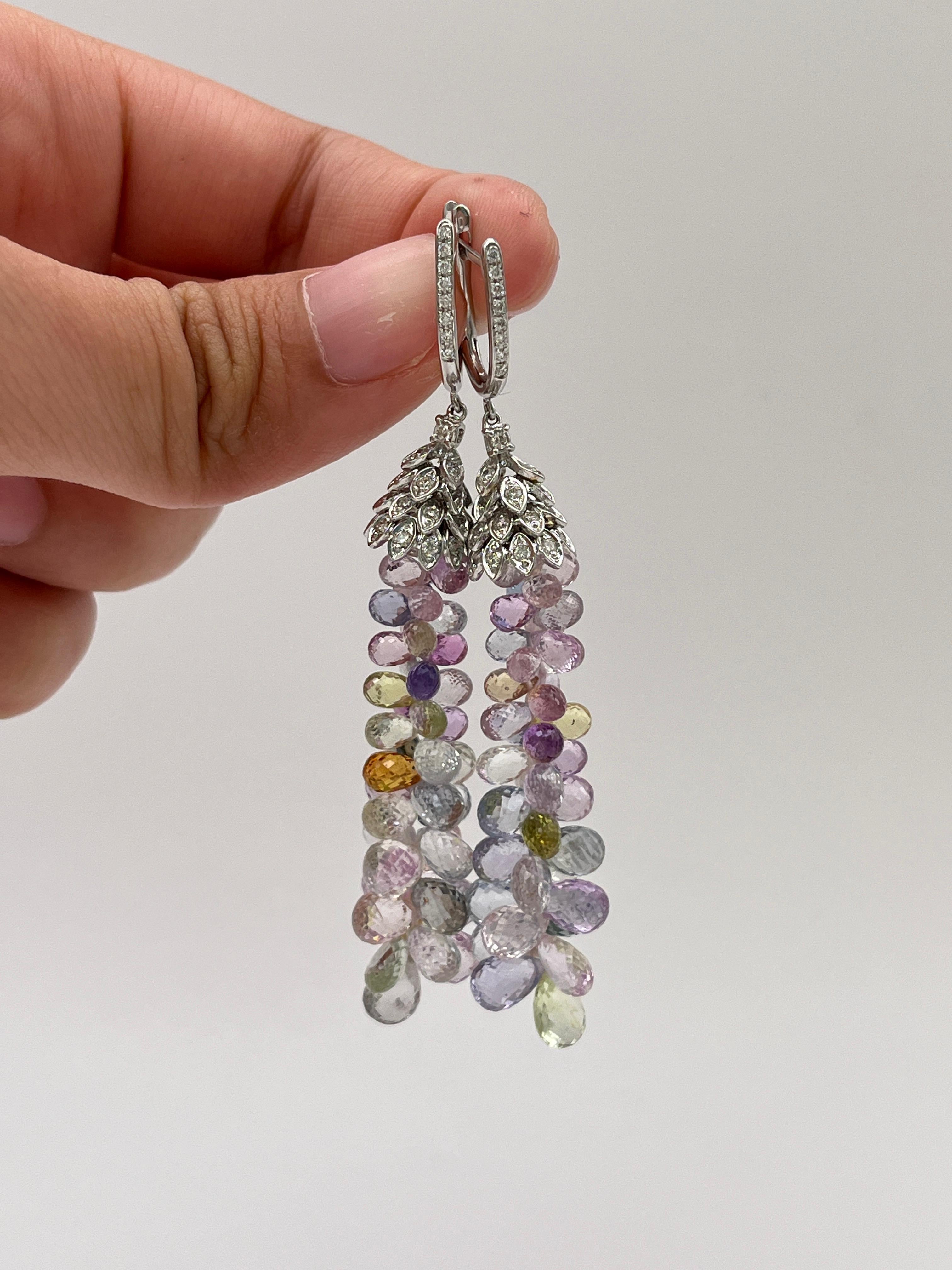 Questi squisiti orecchini a goccia briolette con zaffiri pastello sono una vera celebrazione della bellezza naturale e della raffinata maestria artigianale. Realizzato a mano in oro bianco 18 carati, ogni orecchino presenta una composizione a