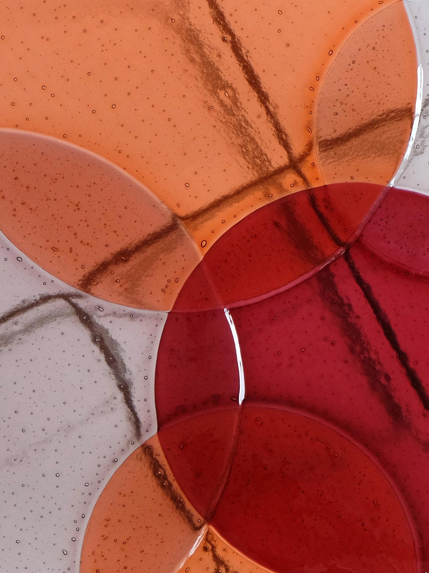 The side tables by Sebastian Herkner are suspended drops of coloured glass which found their inspiration in the particularity of the glass fusing technique. Through the process the perfectly cut glass circles are transformed: their contours get