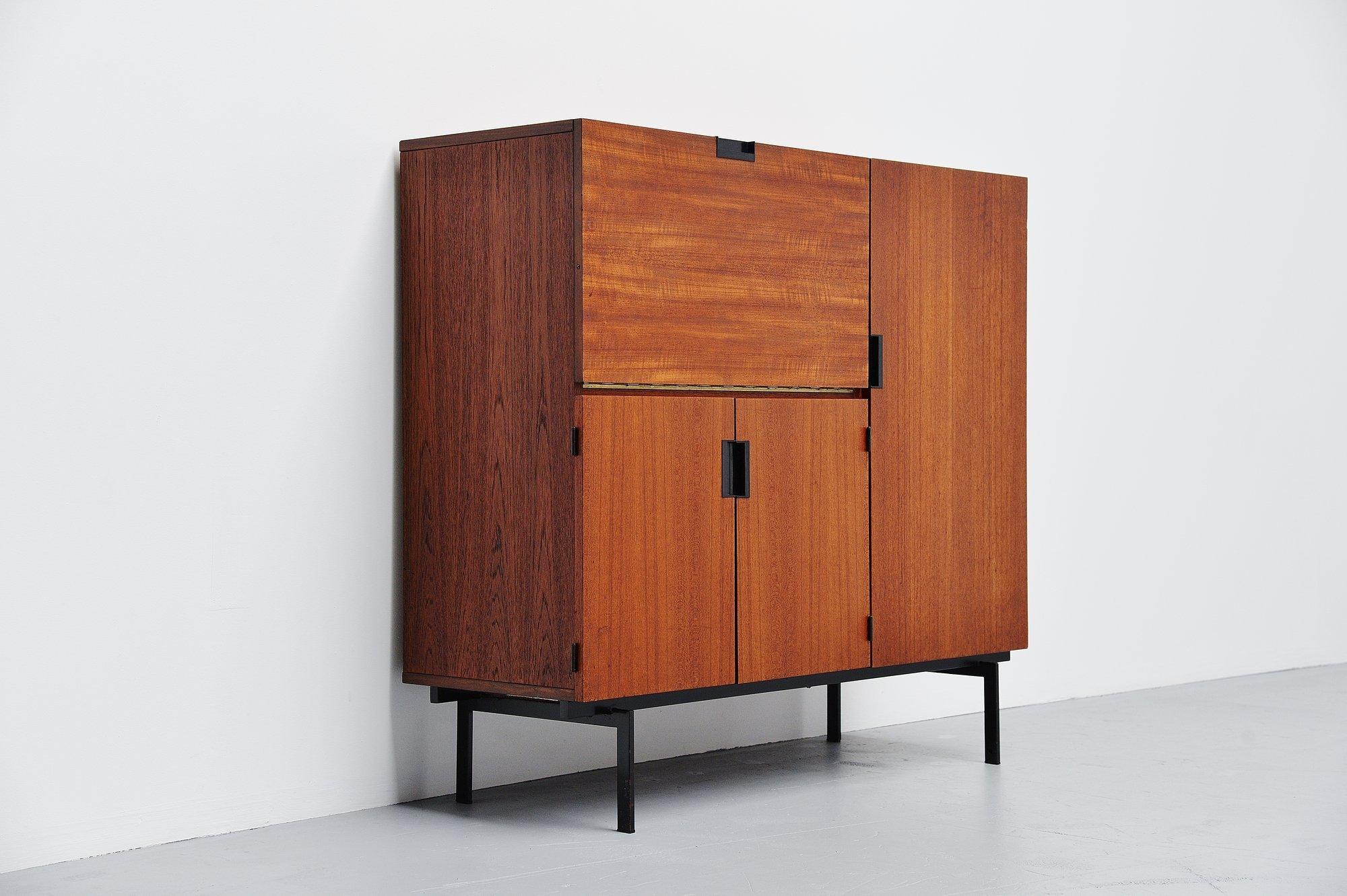 Very nice teak wooden cabinet designed by Cees Braakman and manufactured by Pastoe UMS, Holland 1958. This is for model CU06 and has a drop down door on the left with white shelves and storage behind, 2 folding doors underneath with a shelve behind