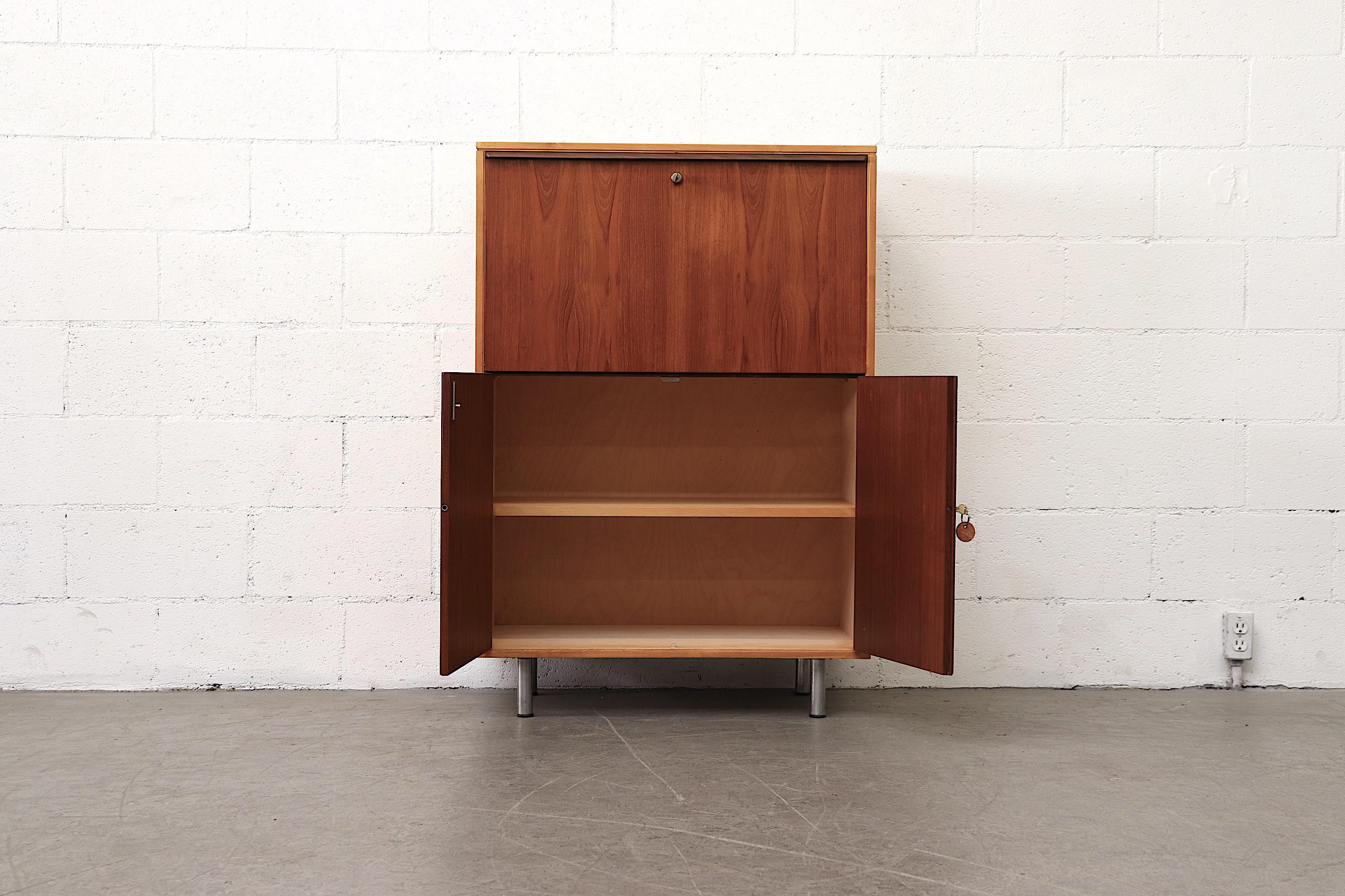 Mid-century two toned Pastoe drop down desk or cabinet with original keys. Striking blonde frame balanced by teak cabinets conceals a large bottom storage space with shelf. A top drop down desk adds additional storage and organization. Original