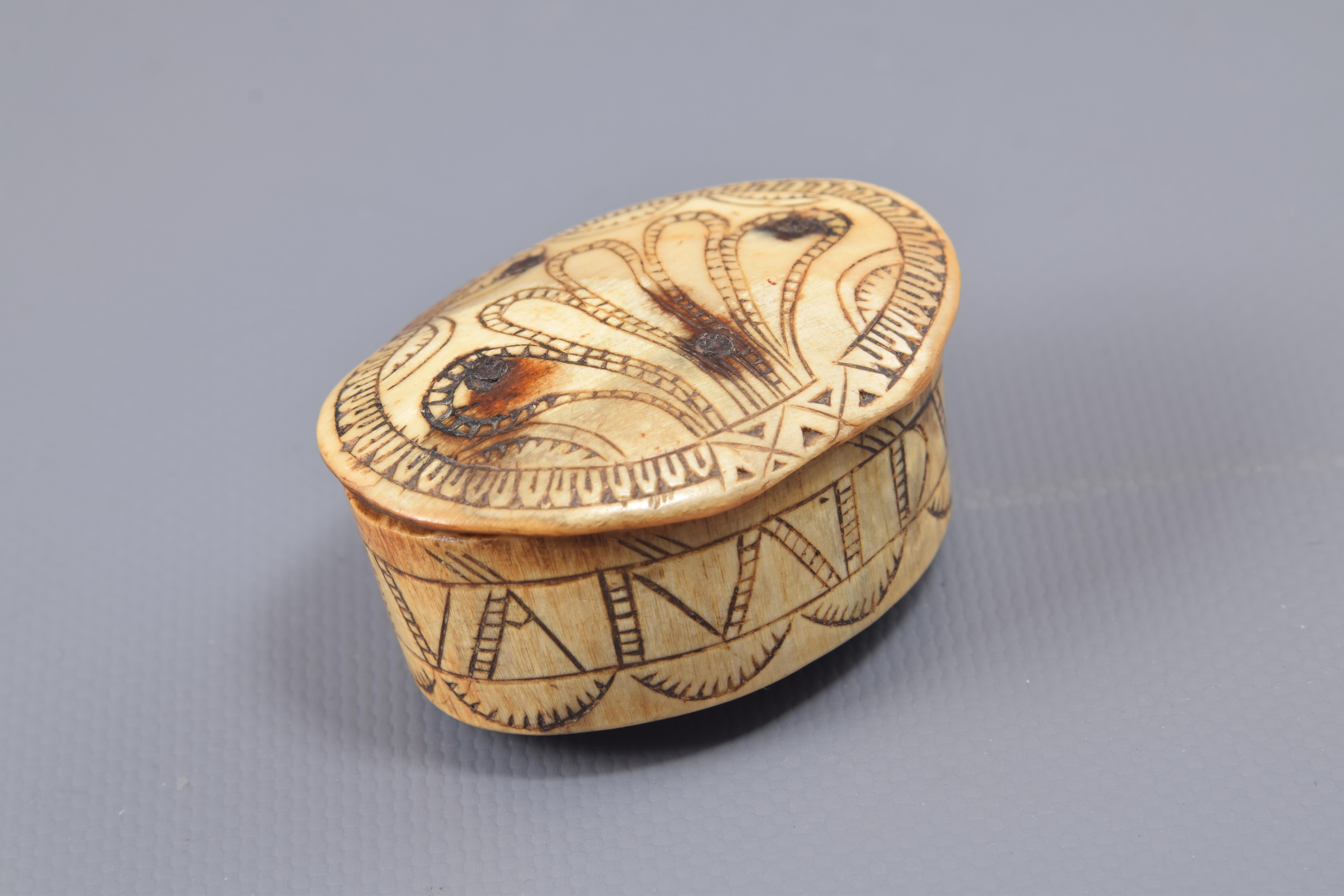 Pastoral box. Asta, metal. Spain, 18th century.
Small oval-shaped box made of carved and engraved flagpole, with metal hinged lid, decorated to the outside with a simple composition based on simplified plant elements and an inscription on the front