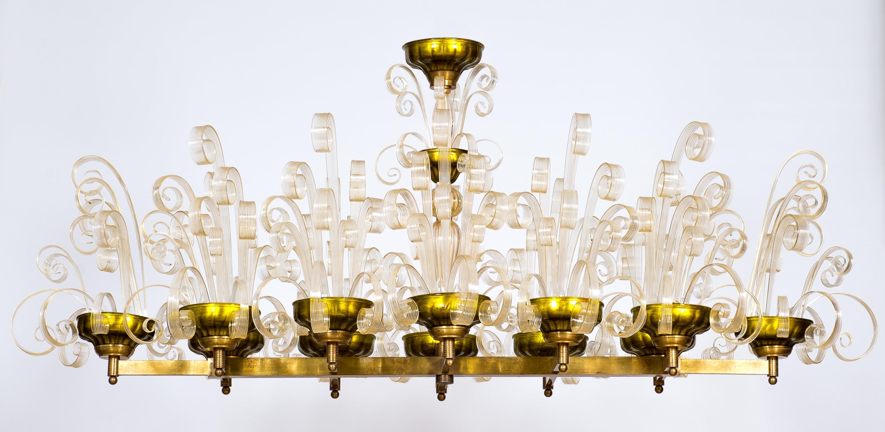Brass Chandelier with Crosiers in Clear Murano Glass and Golden Leaf Italy 1970s

Entirely handmade of brass and blown Murano glass, this chandelier is a unique creation by the Italian artist and designer Giovanni Dalla Fina. The chandelier is