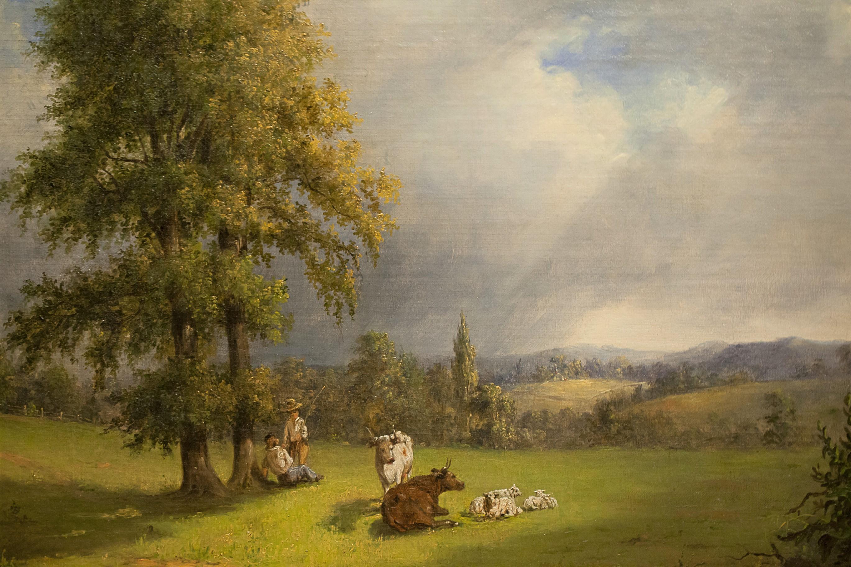 A bucolic scene of a pasture, probably in Pennsylvania, with two people and several cows and calves in a rolling landscape with one large tree in the foreground and a partly-cloudy sky. This painting was previously sold by the Vose Galleries of
