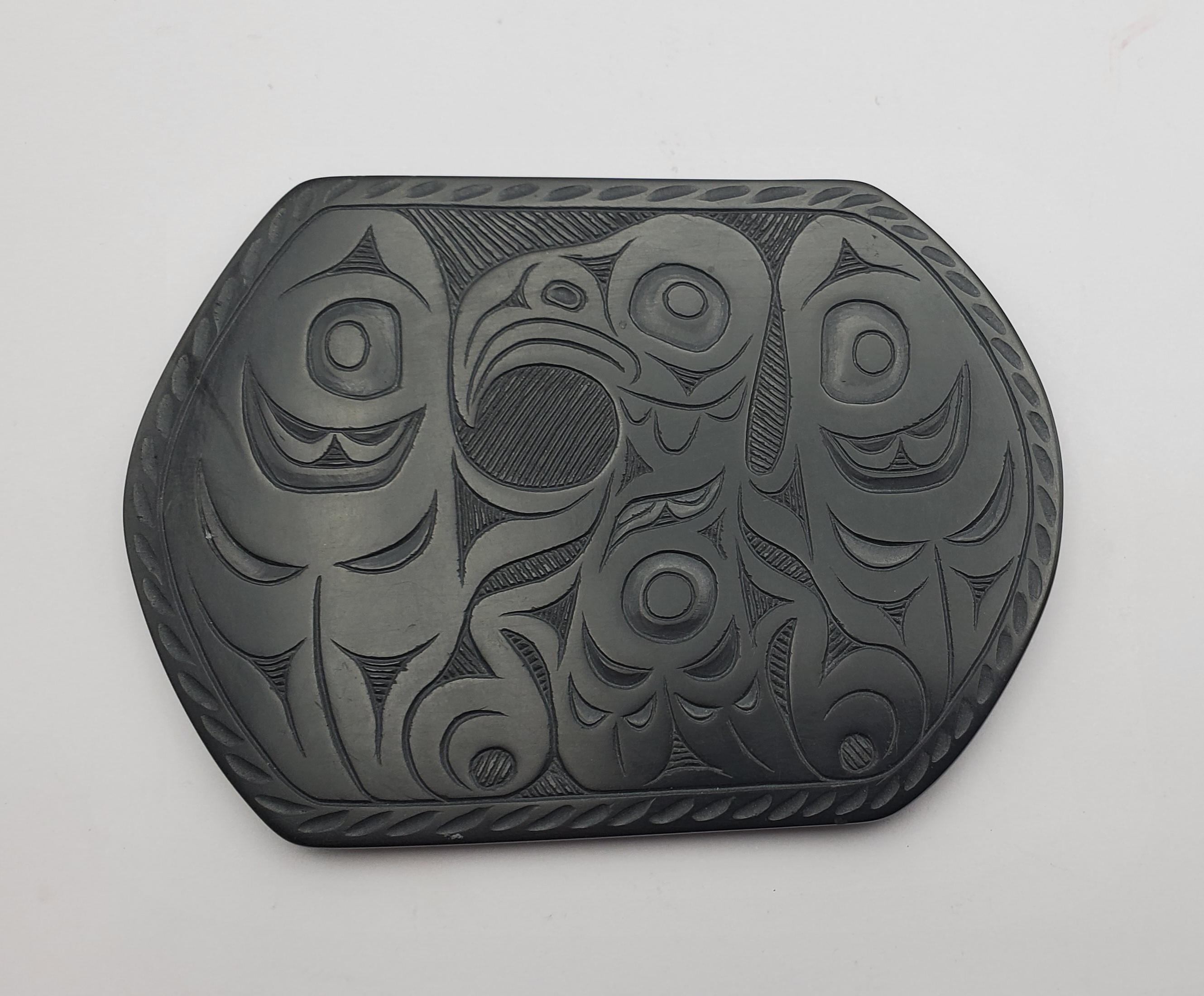 Auffälliges Argillit-Tablett des Schnitzers Pat Dixon von den First Nations. Argillit ist ein hartes schwarzes Gestein, das auf den Queen Charlotte Islands gefunden wird. Die Rückseite des Tabletts ist mit Pat Dixon 8/96 signiert.

Der