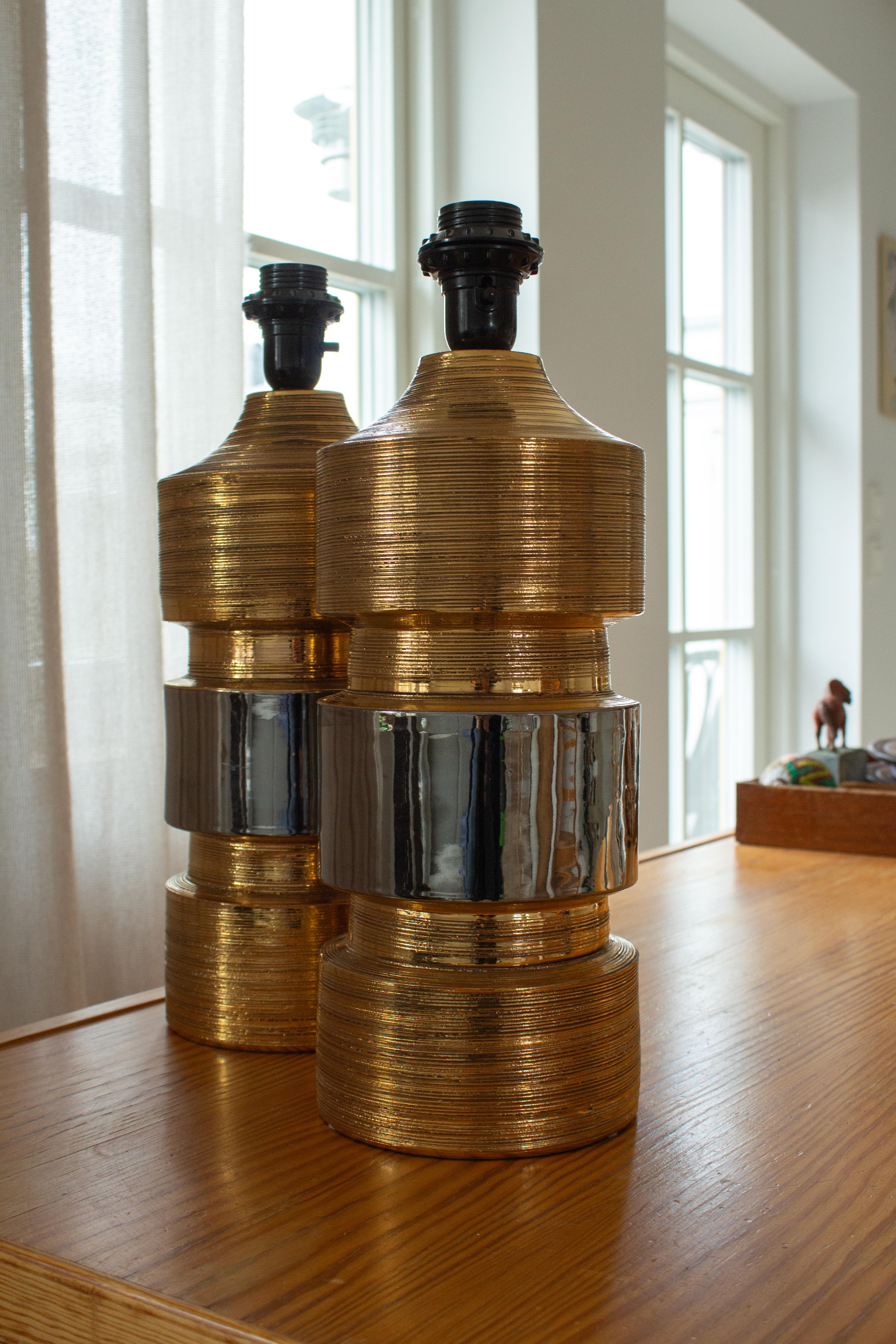 Fabuleuse paire de lampes de table en céramique de la famille de designers italiens Bitossi, conçues et fabriquées par Bergboms en Suède. Les lampes sont en excellent état. Les céramiques sont recouvertes d'une glaçure métallique dorée avec une