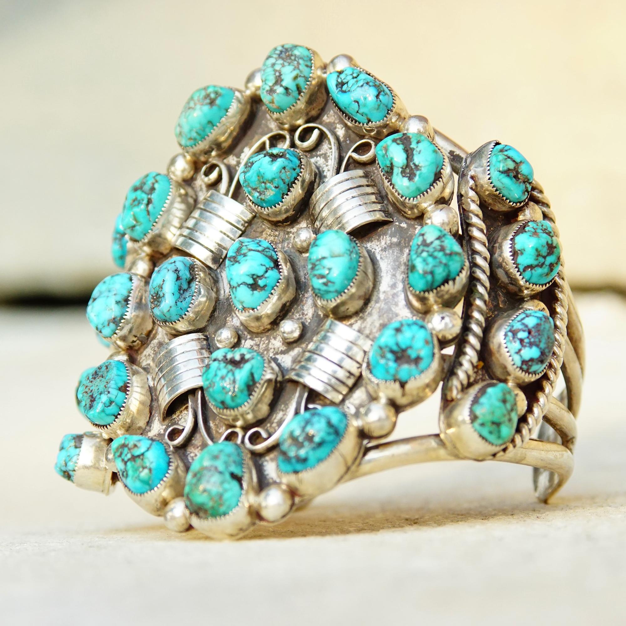 A HUGE Native American sterling silver turquoise cuff by Navajo jewelry maker Pat Platero. This incredibly badass cuff features 25 marbled turquoise stones, all roughly the same size,  organized in jagged bezels across 3 silver panels. The main oval